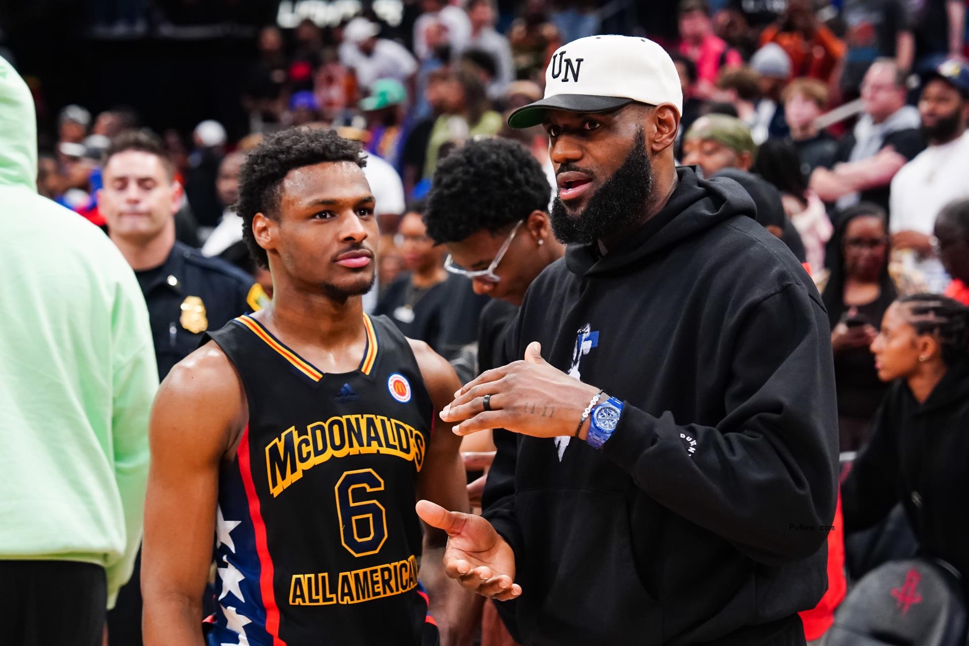 Bro<i></i>nny James and LeBron James talking on a basketball court.