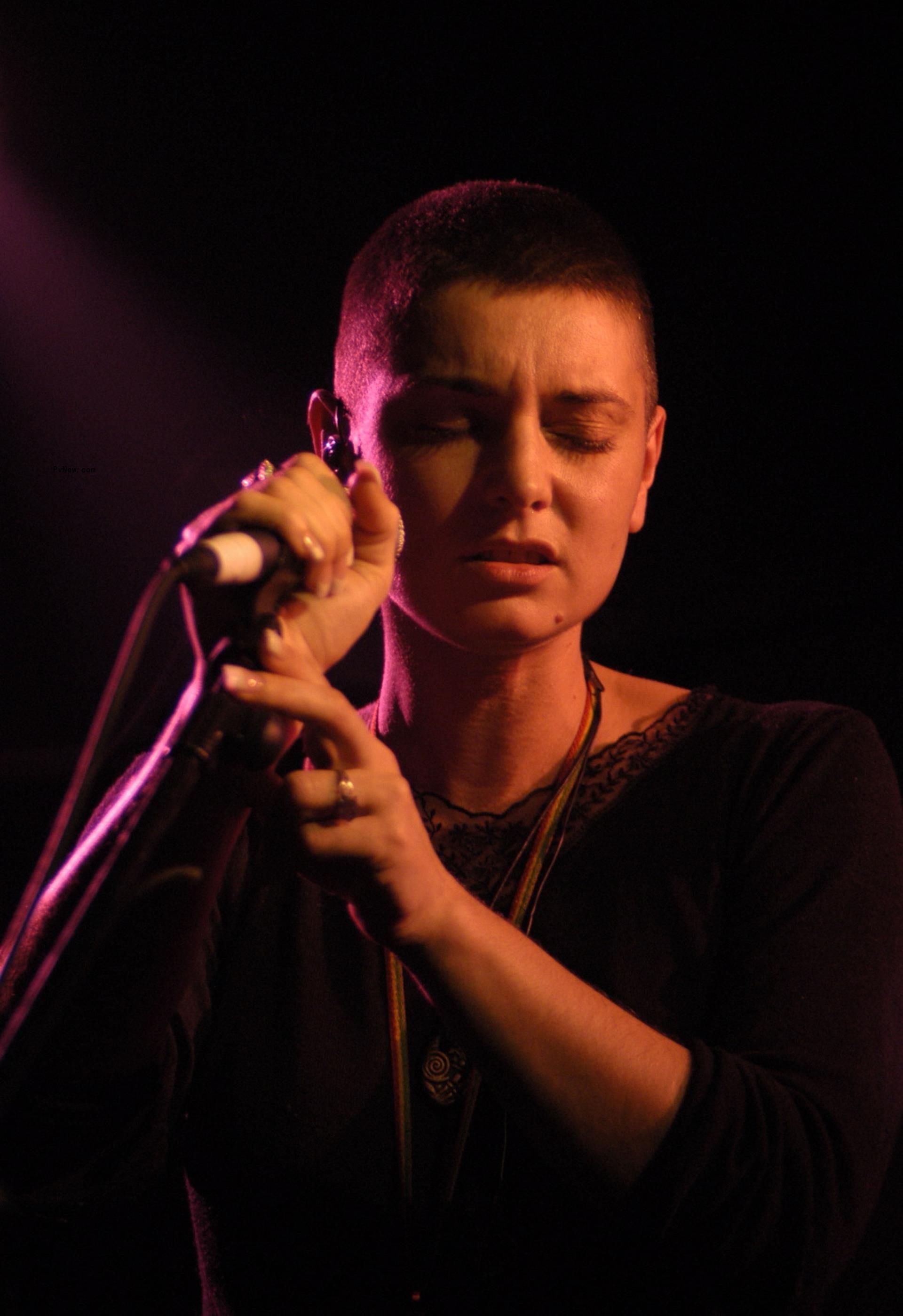 Sinéad O'Co<i></i>nnor singing into a microphone.