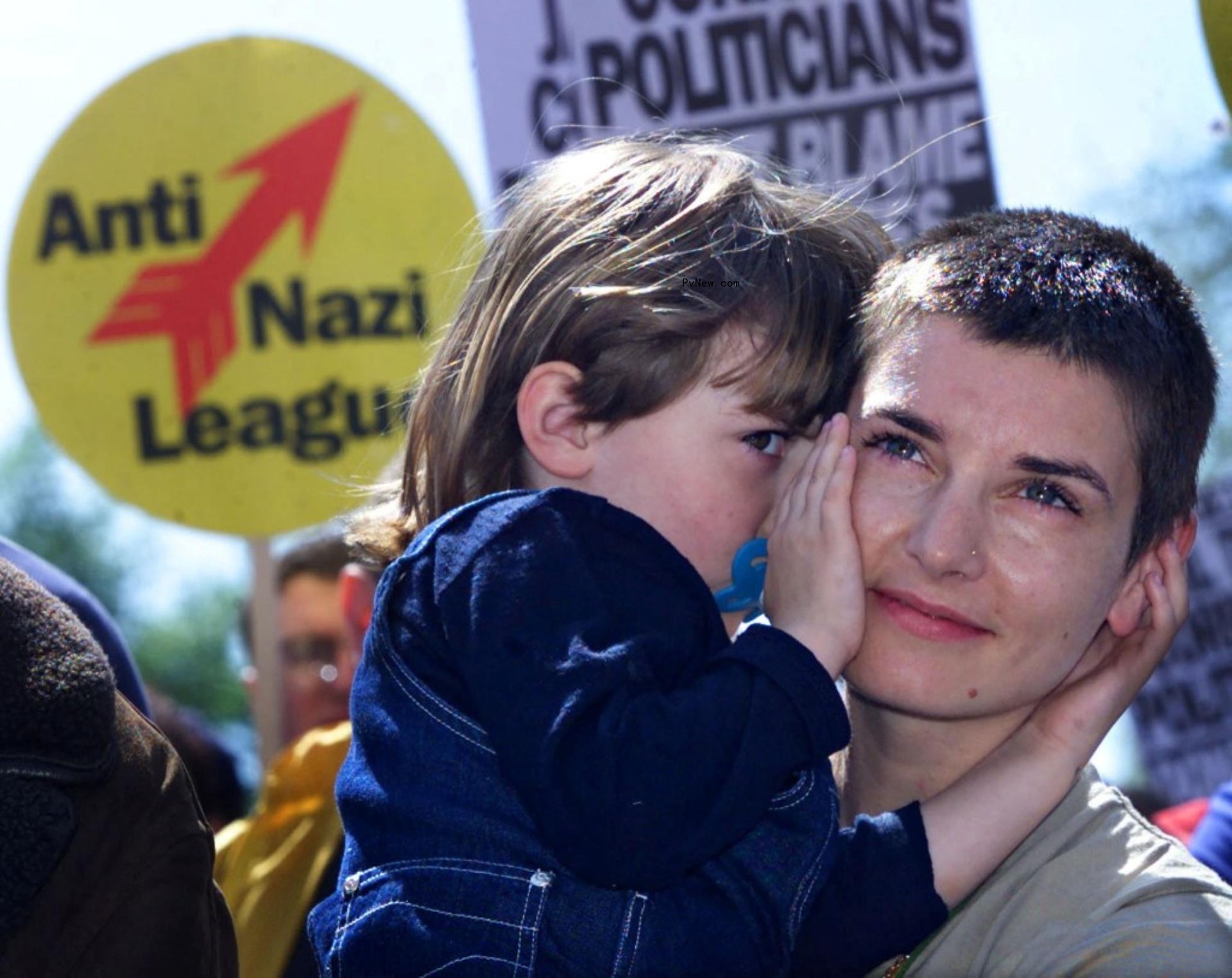 sinead o'co<i></i>nnor holding one of her children with an anti-nazi league protest sign behind them
