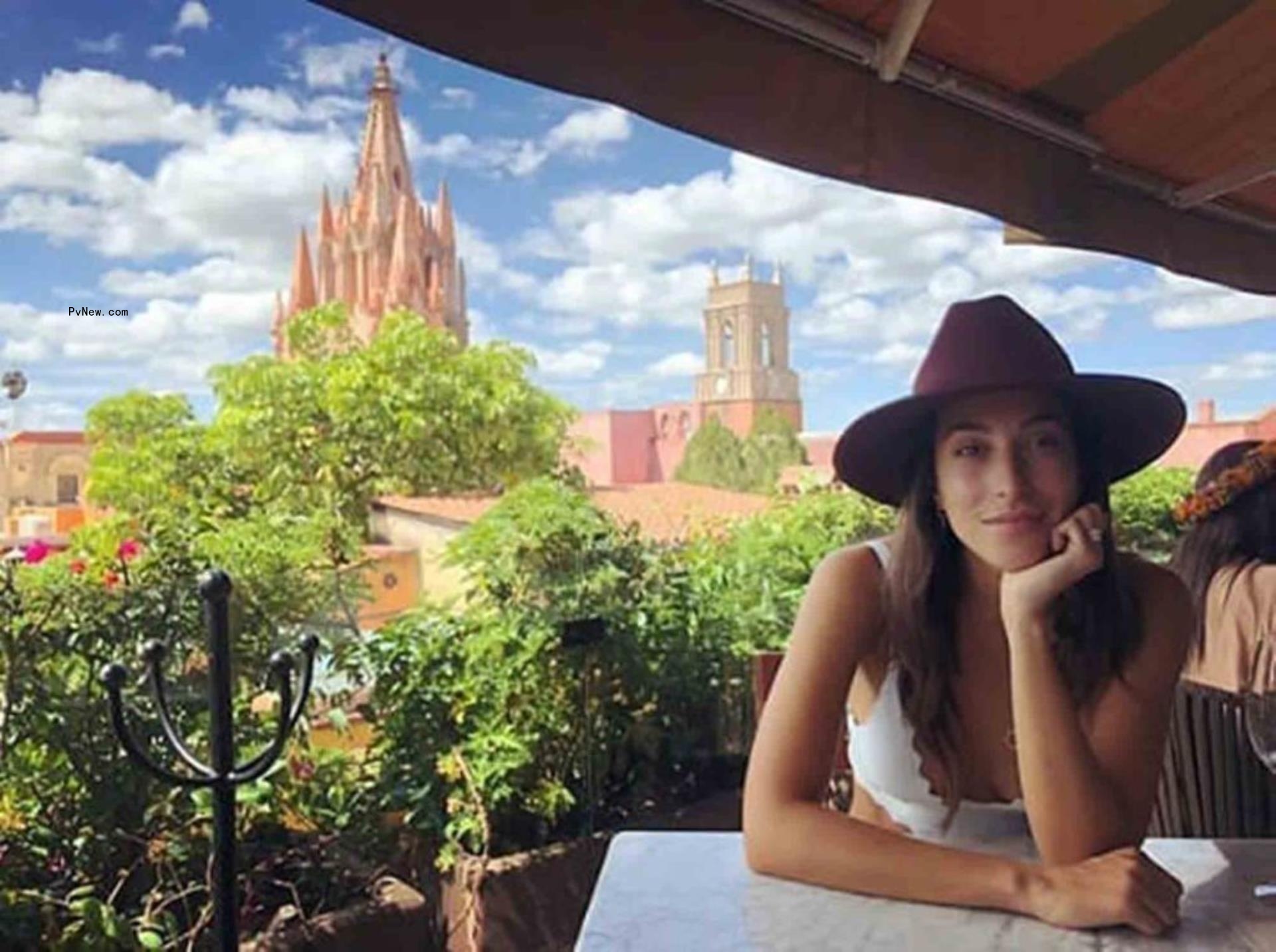 ines de ramon sitting at a table with a cathedral behind her