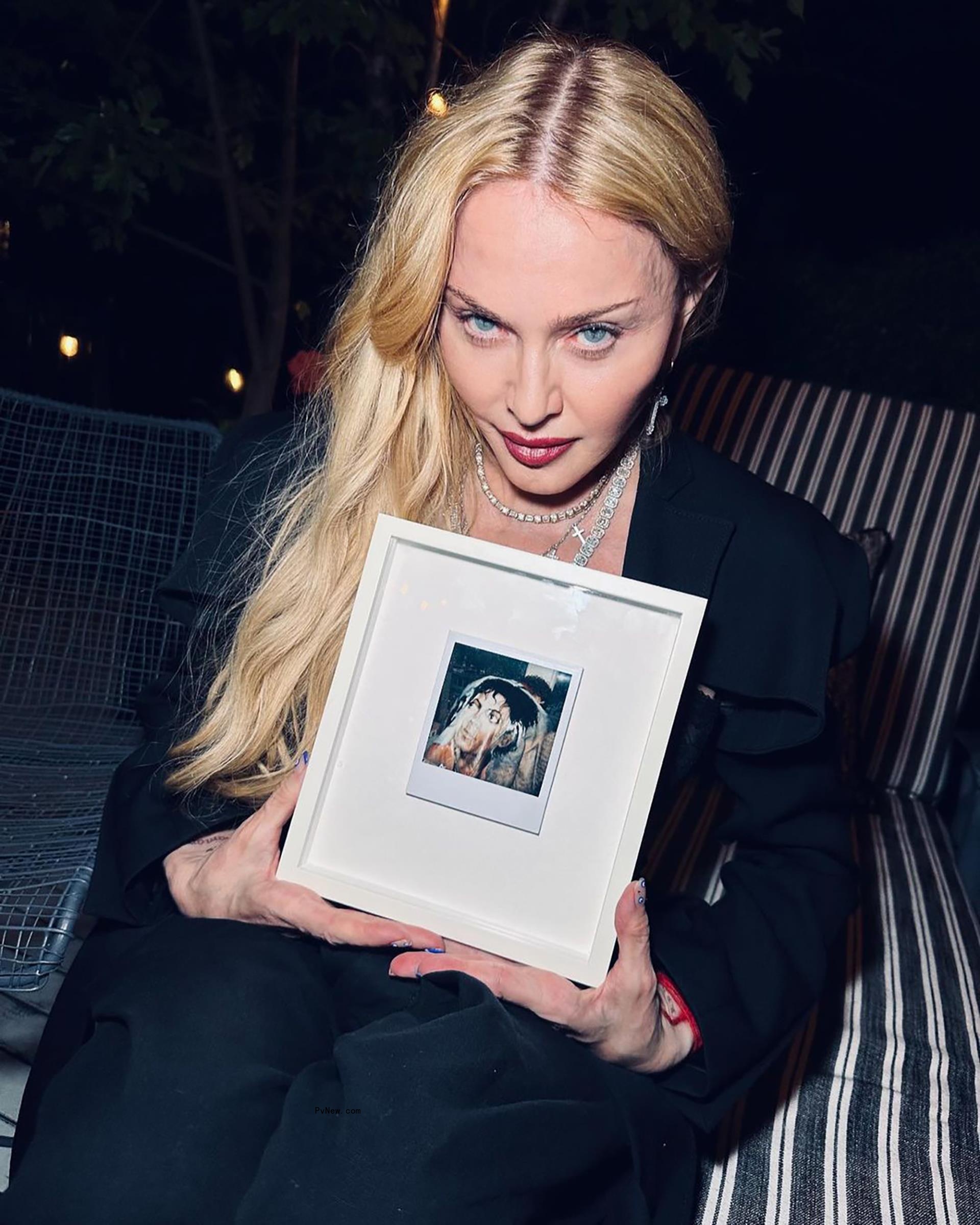 Mado<i></i>nna holding up a f<i></i>ramed Polaroid