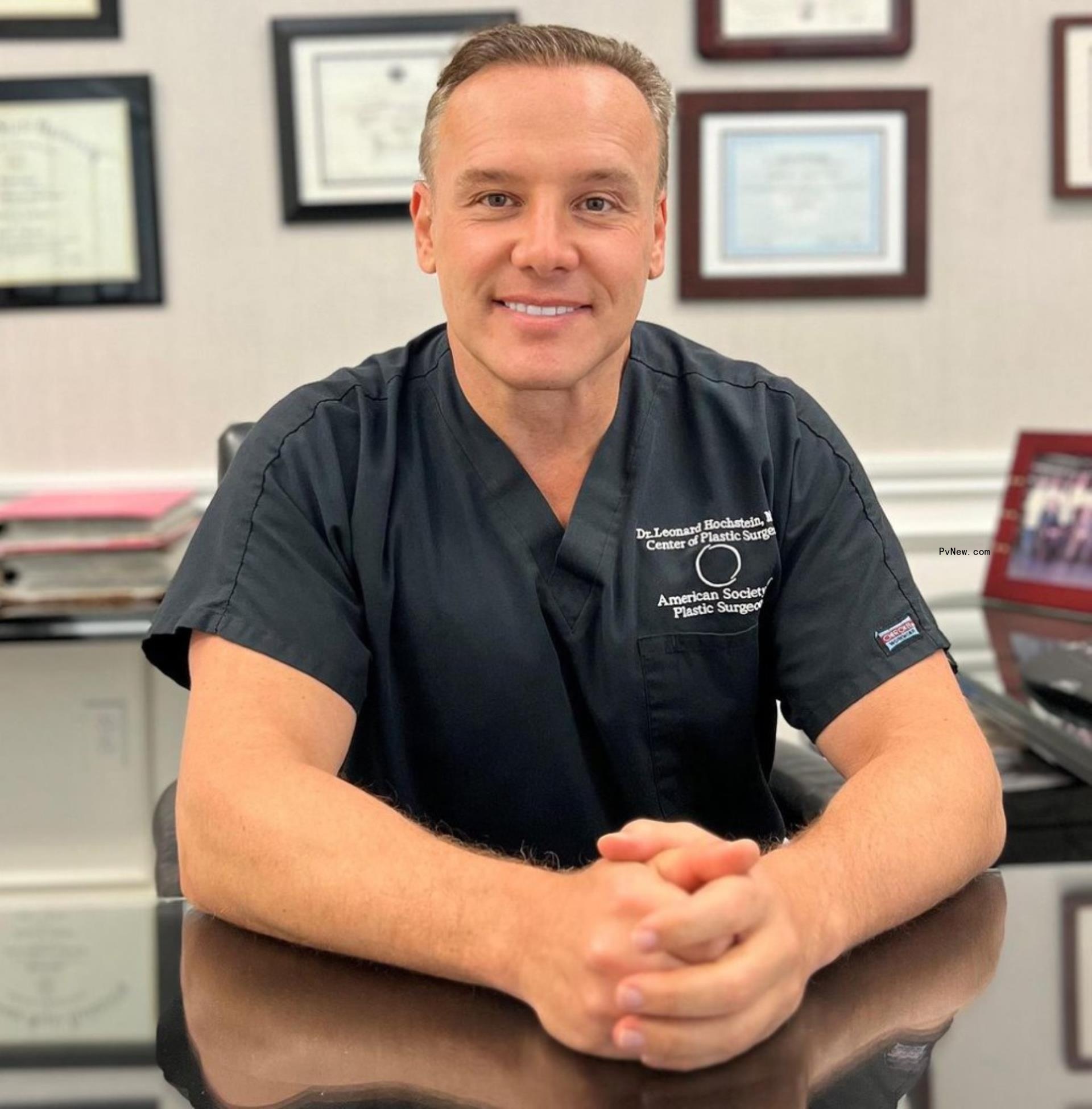 lenny hochstein sitting at his desk dressed in scrubs