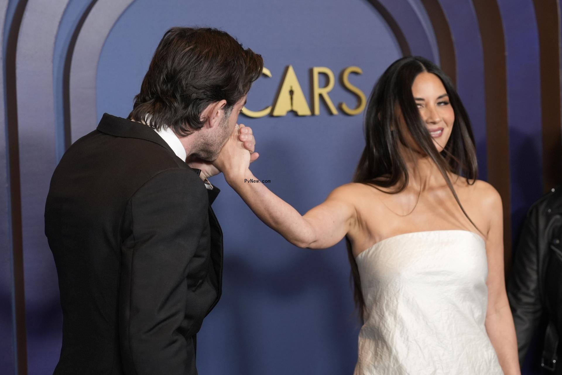 John Mulaney and Olivia Munn walking a red carpet together.