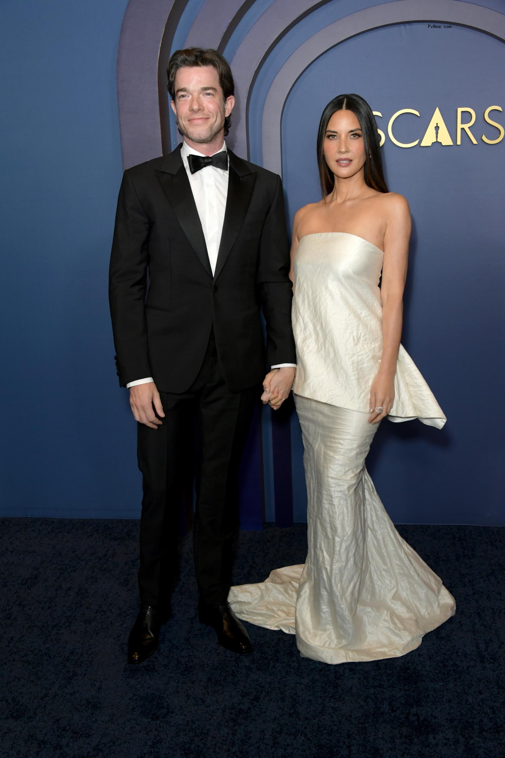 John Mulaney and Olivia Munn walking a red carpet together.