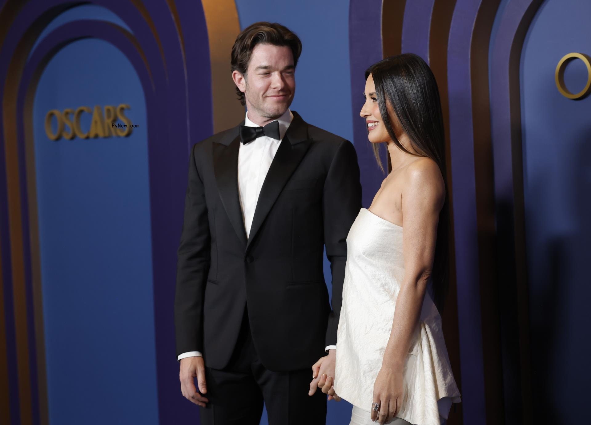 John Mulaney and Olivia Munn walking a red carpet together.