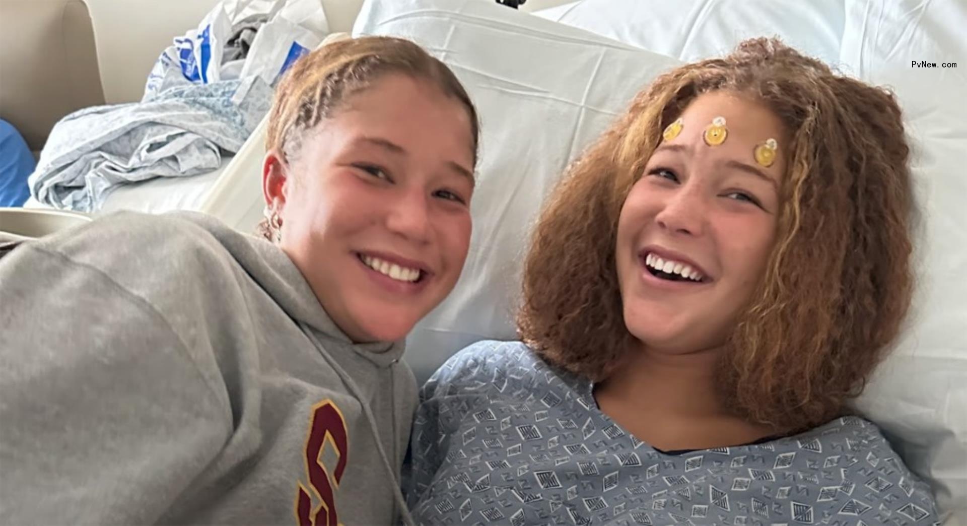 isabella strahan lying in a hospital bed with three nodes on her forehead and her twin, sophia, lying next to her