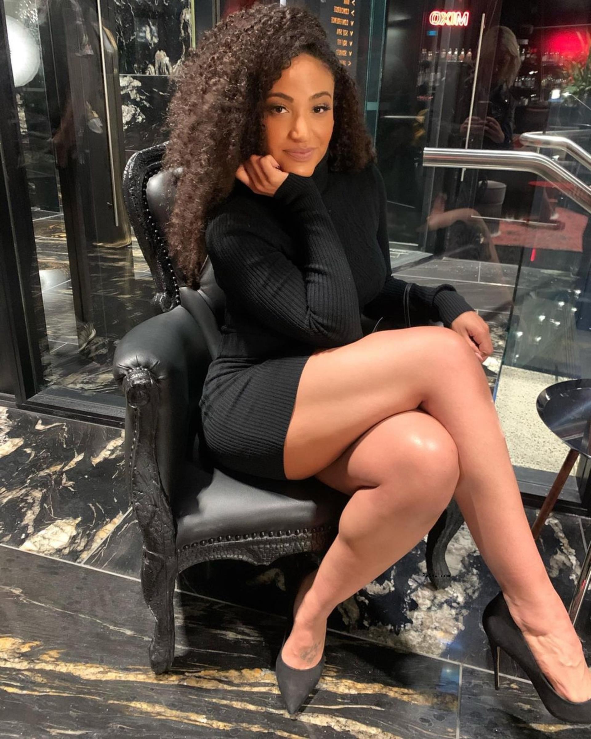 Shirlene Quigley sitting down and posing in a black dress.