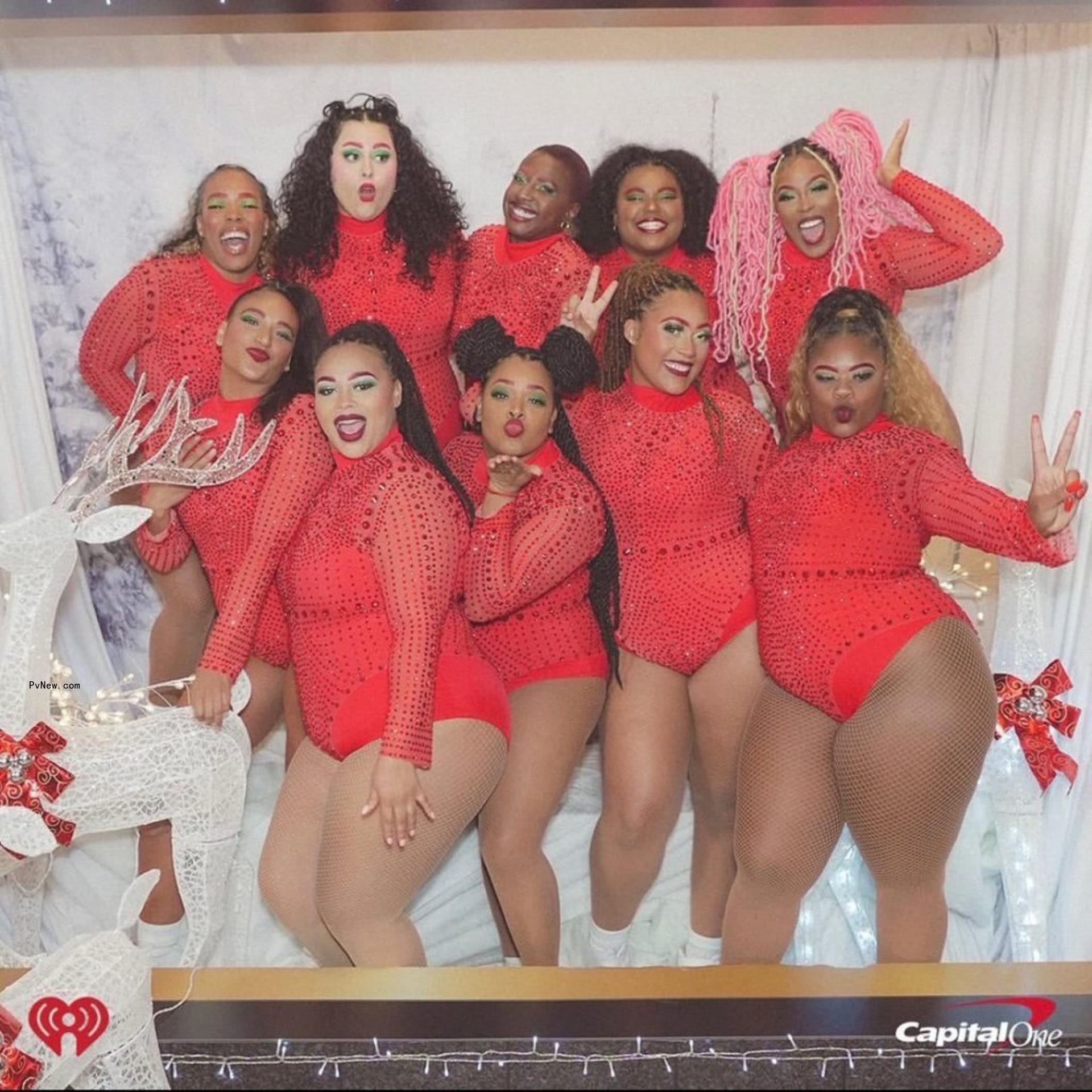Lizzo's dancers posing for a pic in matching red outfits.