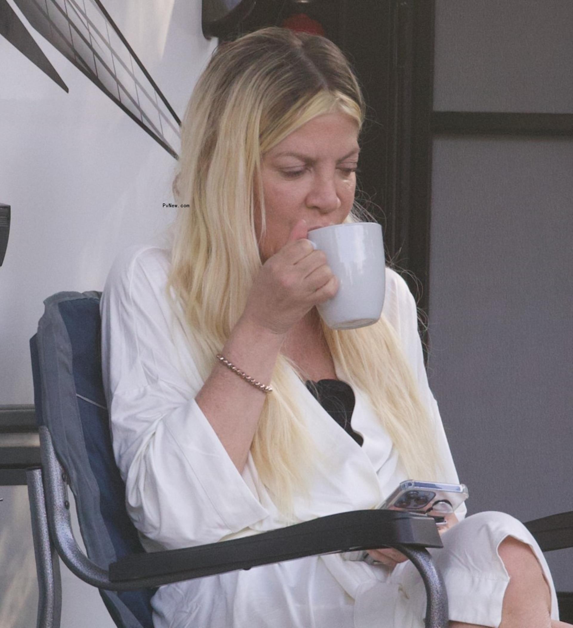 Tori Spelling sipping from a coffee cup at her campsite.