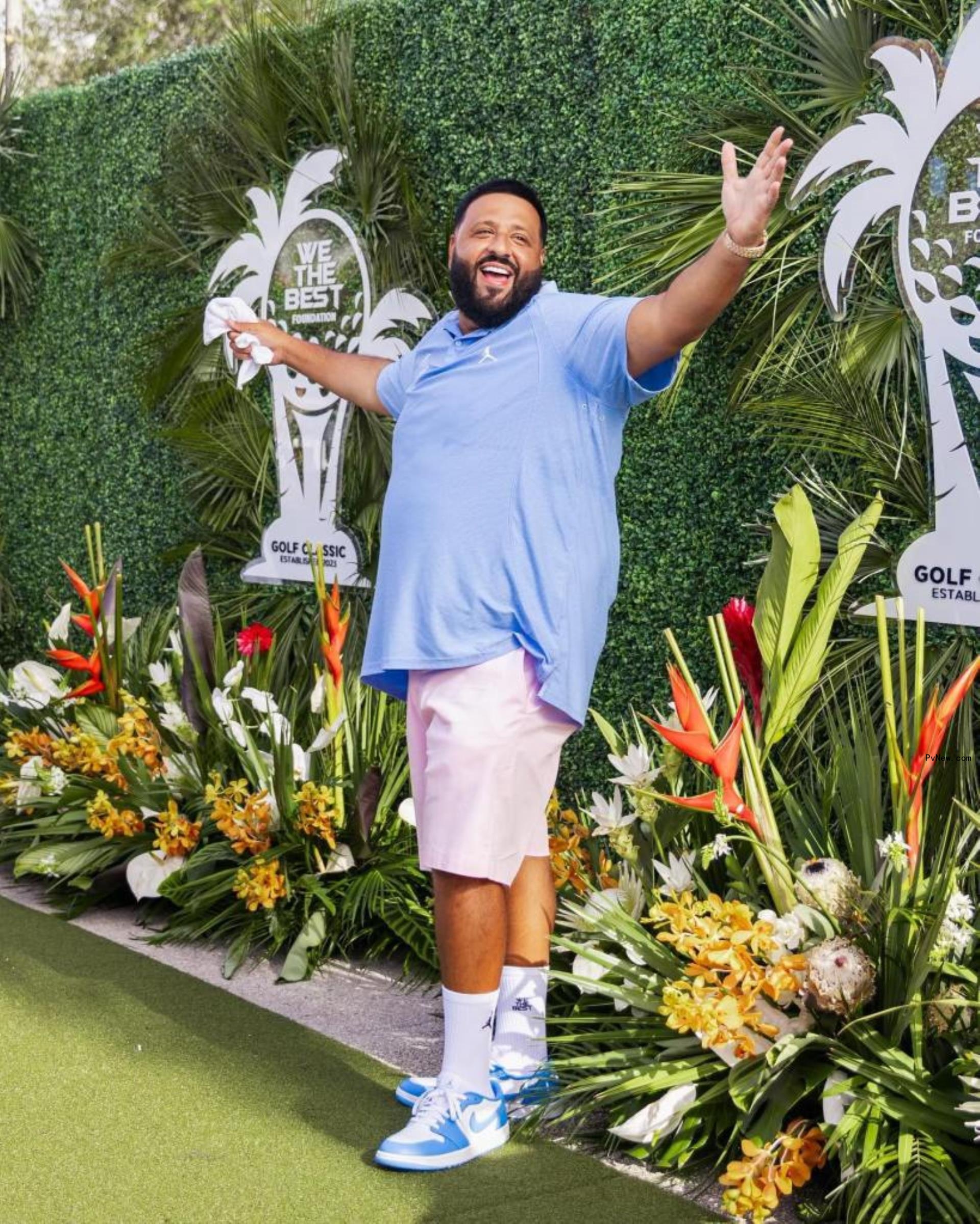 DJ Khaled in blue shirt and pink shorts of green carpet.