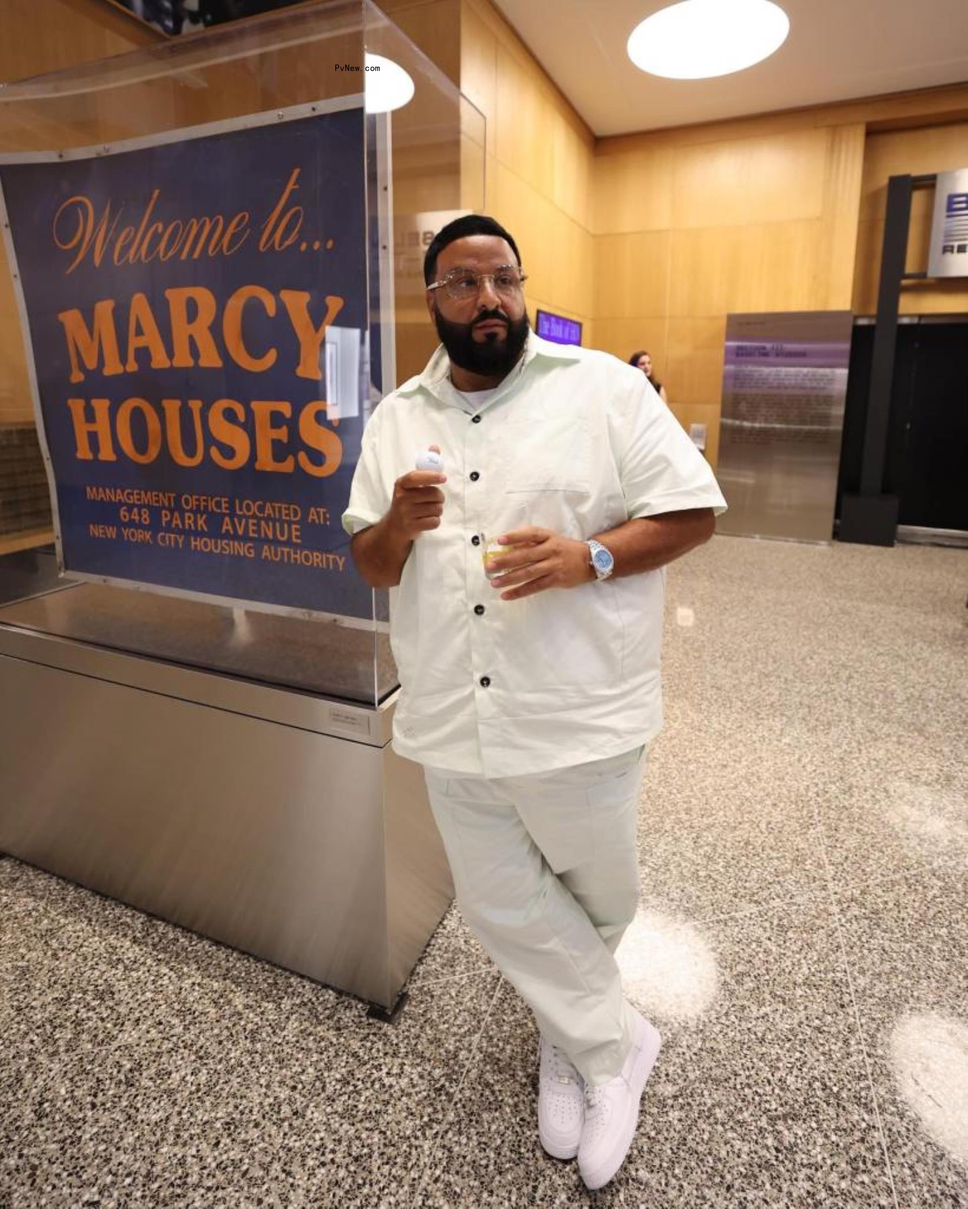 DJ Khaled wearing white posing by Marcy Houses sign.