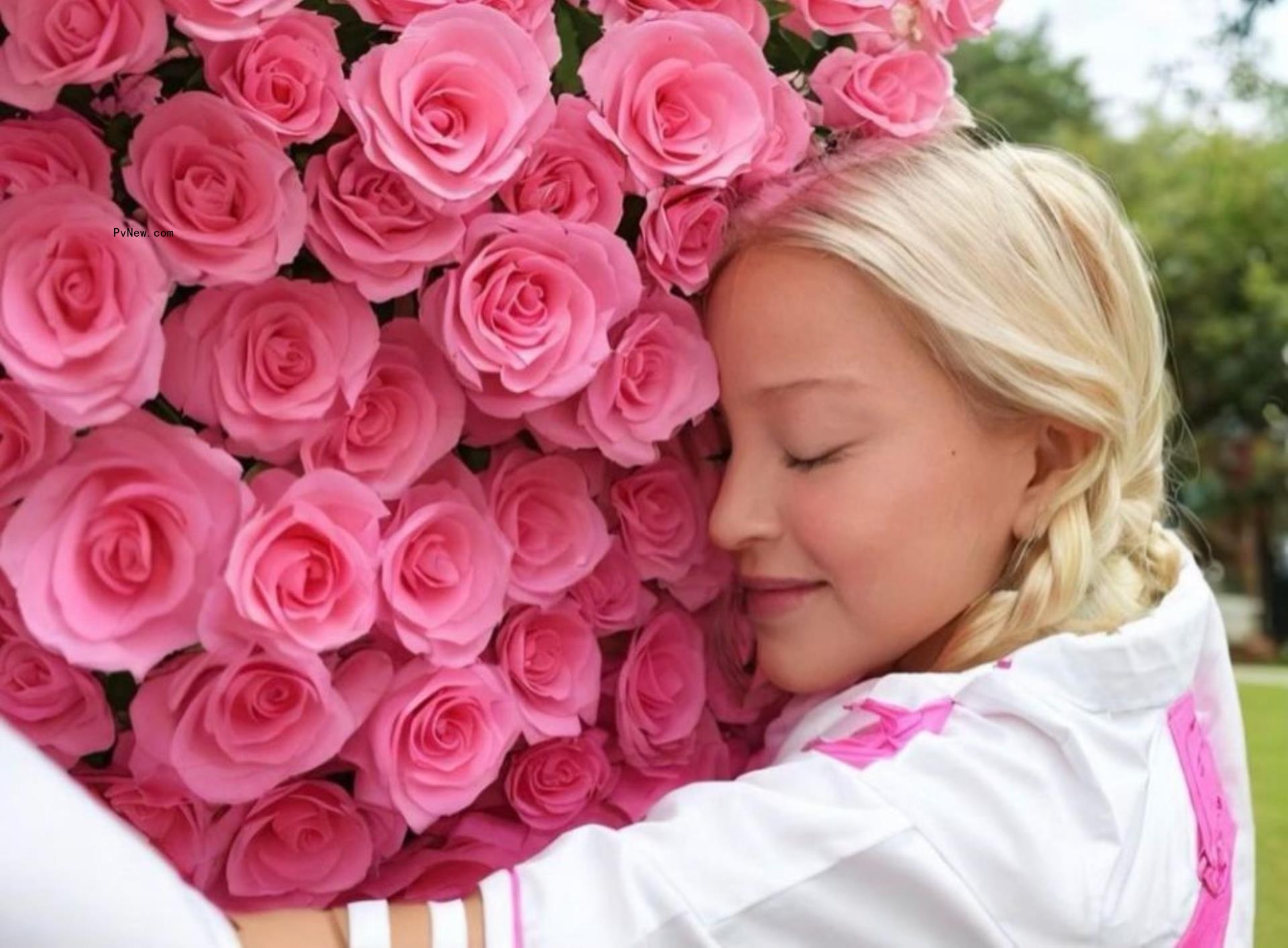 Mado<i></i>nna hugging a wall of roses.
