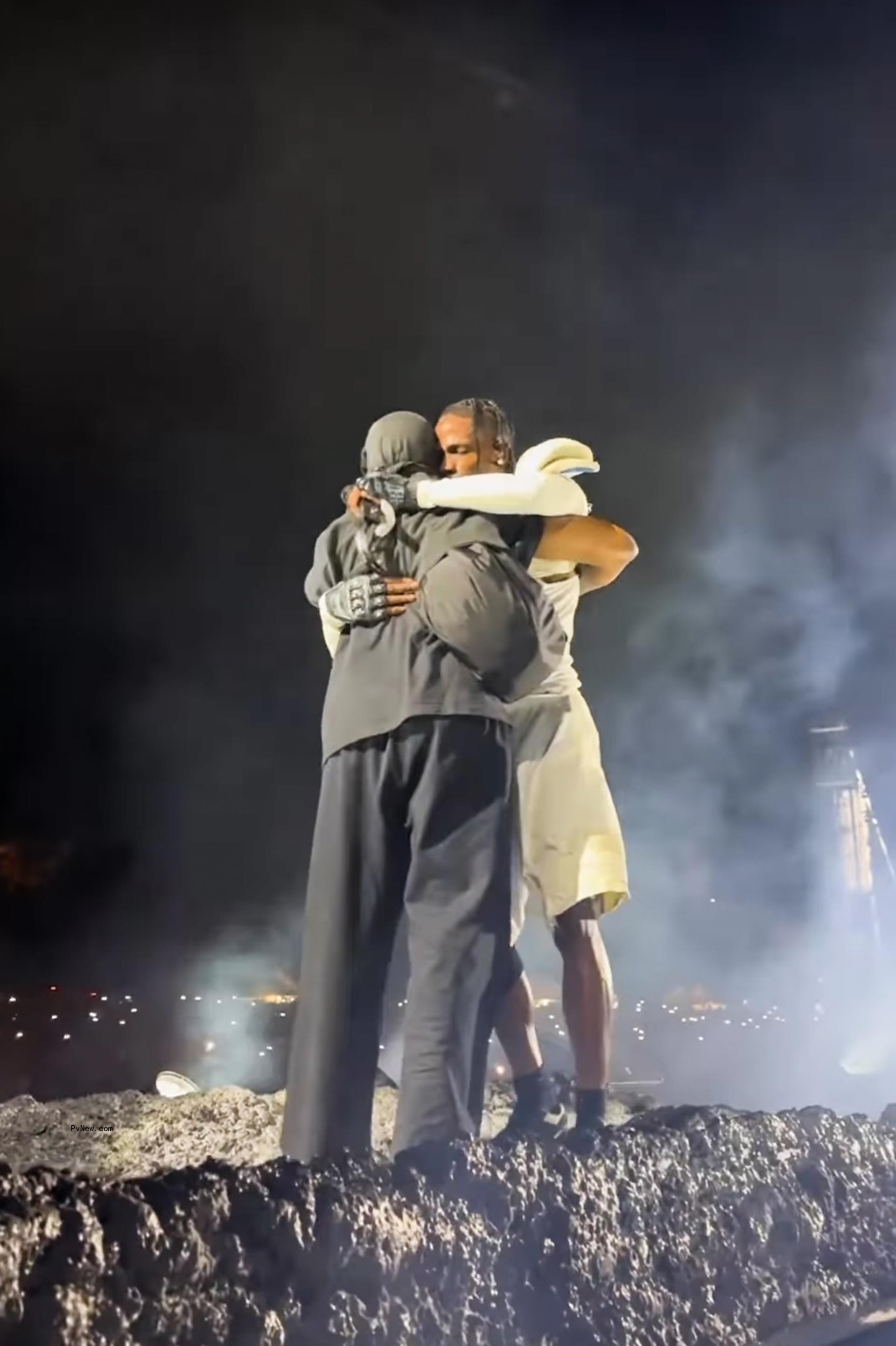 Kanye West and Travis Scott hugging onstage.