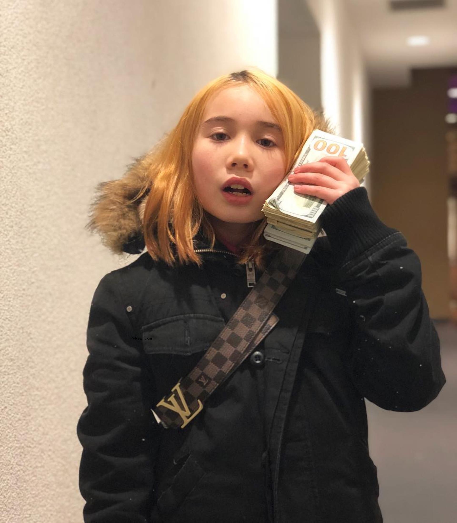 Lil Tay holding a stack a cash to her ear.