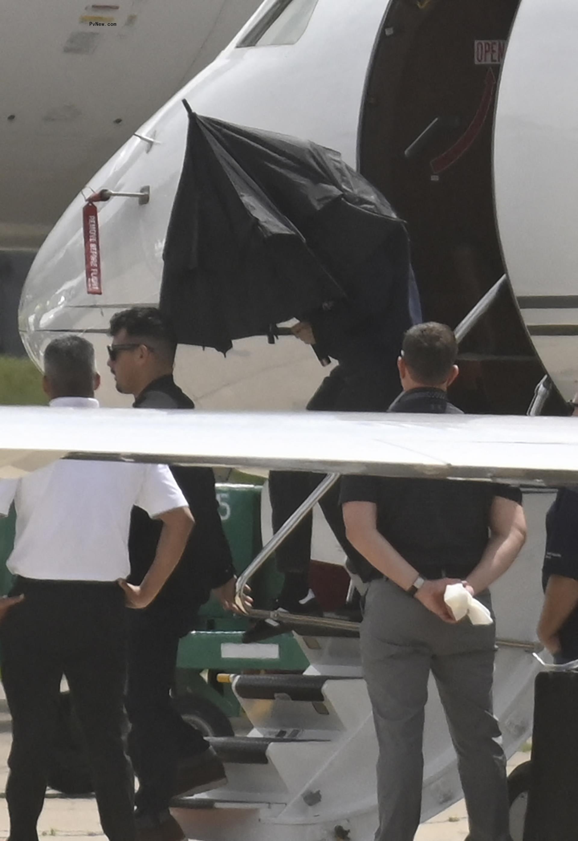 taylor swift co<i></i>ncealing herself with an umbrella as she walks off a private jet