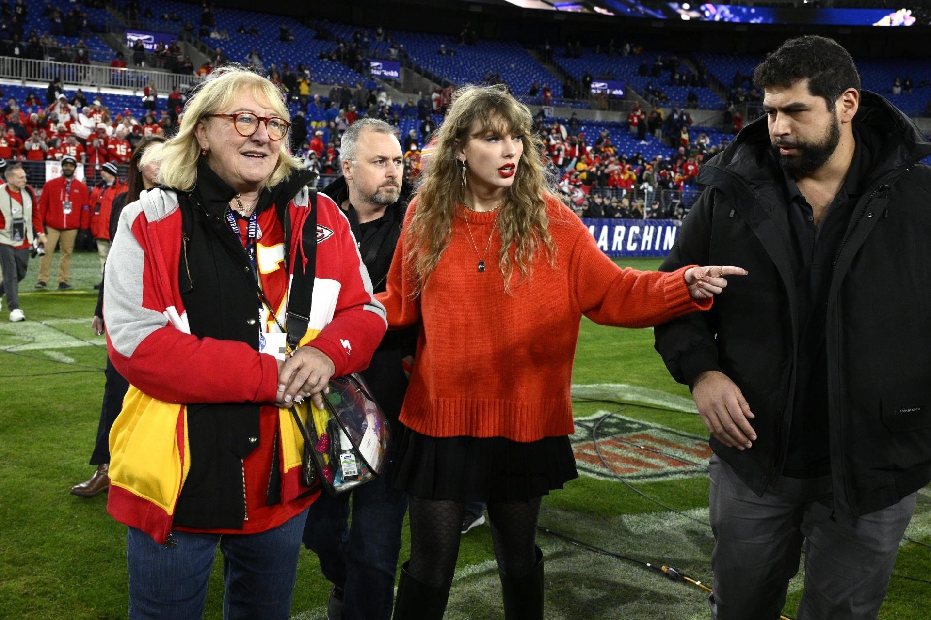 Taylor Swift, center, and Do<i></i>nna Kelce walk on the field after the Kansas City Chiefs won the AFC Champio<i></i>nship NFL football game against the Baltimore Ravens, Sunday, Jan. 28, 2024, in Baltimore.