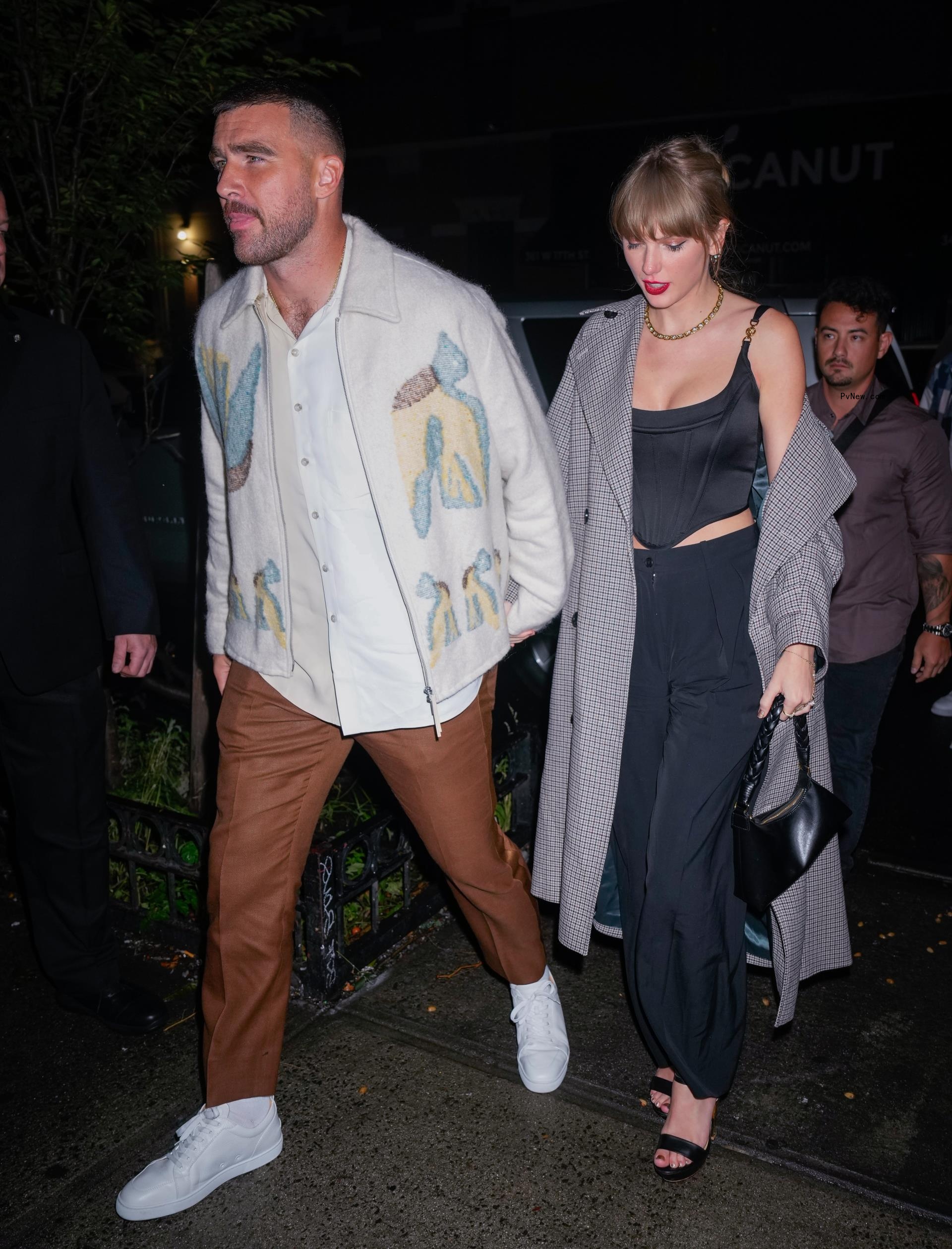 Taylor Swift and Travis Kelce holding hands.