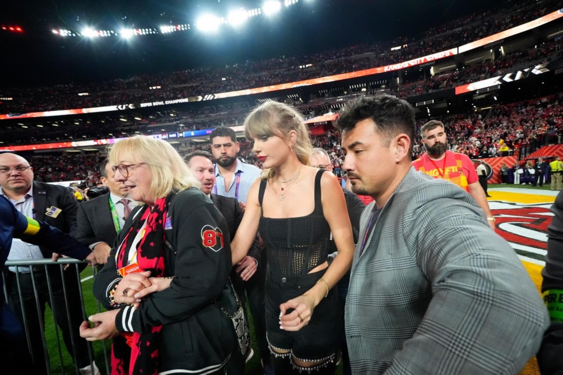 do<i></i>nna kelce leading taylor swift on the football field