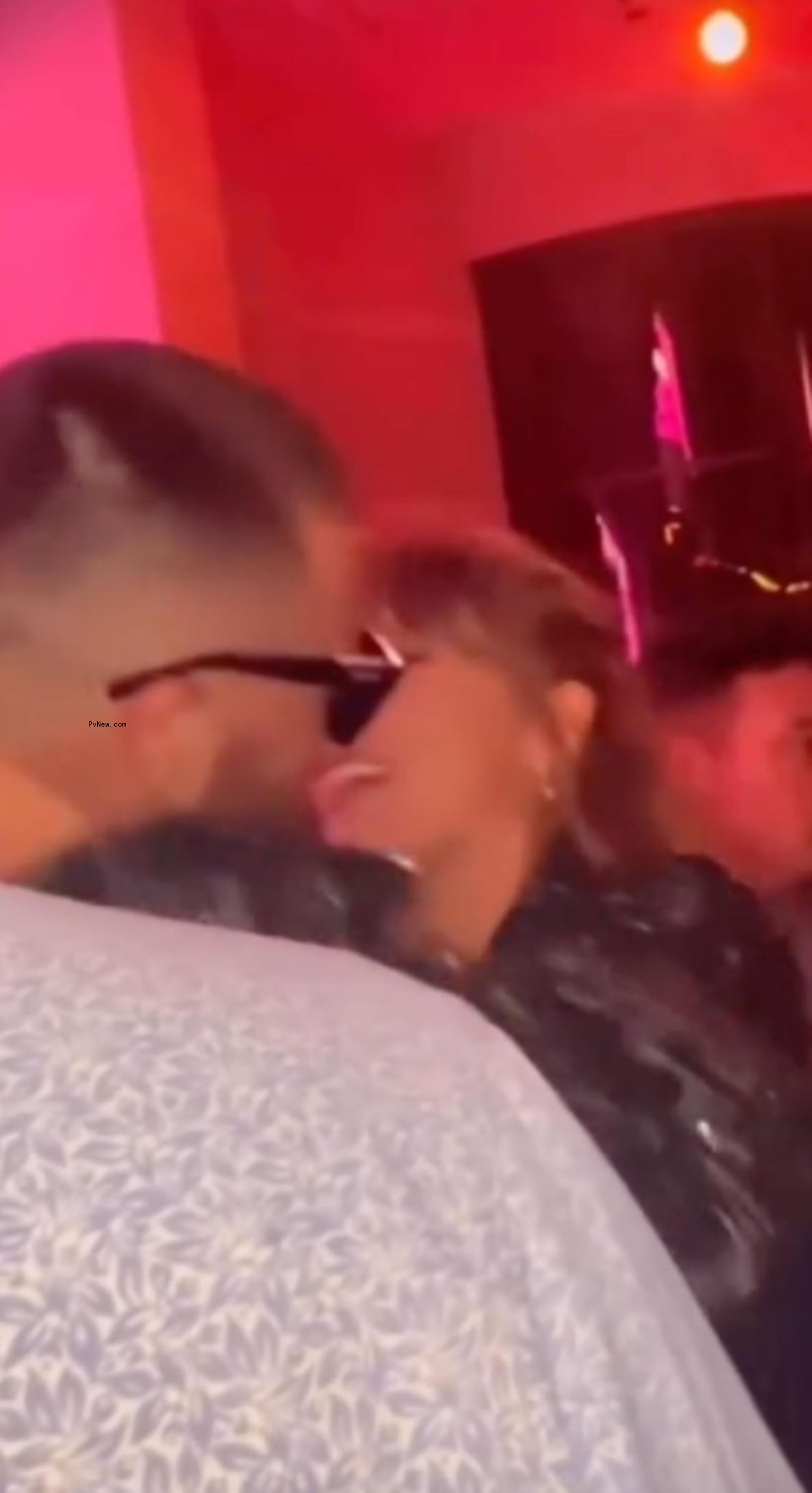 blurry image of taylor swift and travis kelce kissing at a club