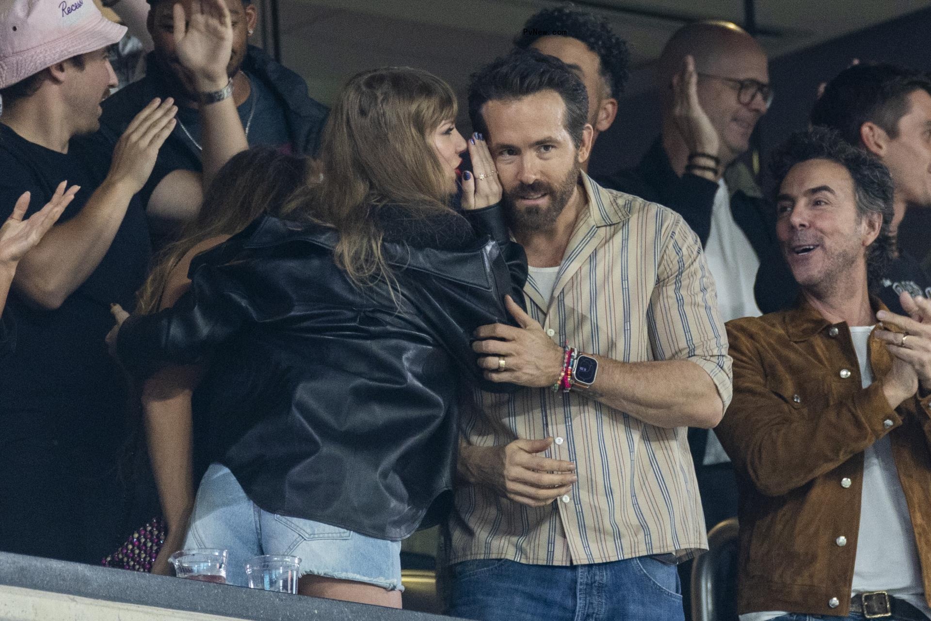 Taylor Swift whispering to Ryan Reynolds.