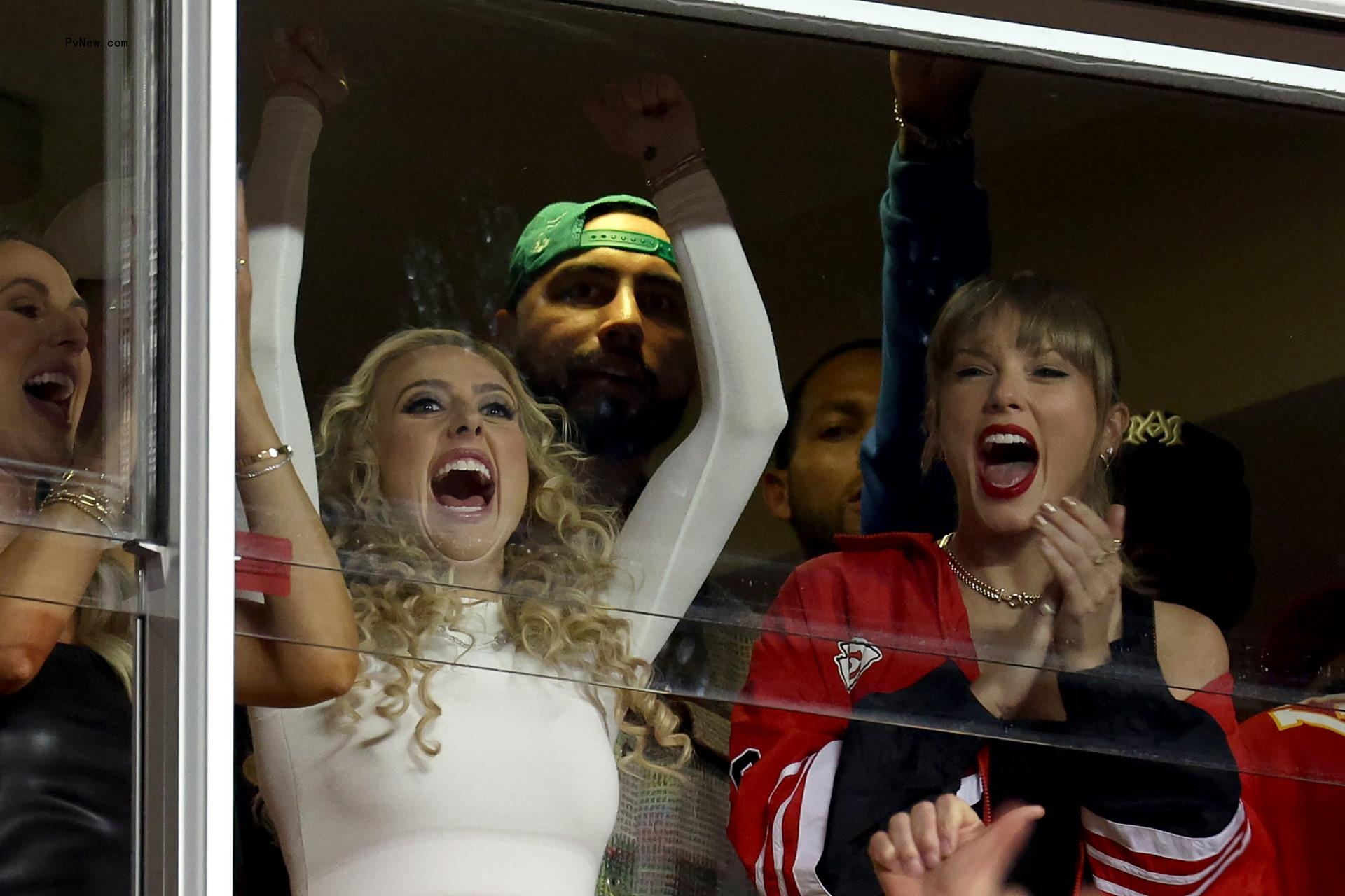 Brittany Mahomes and Taylor Swift cheering from an NFL stadium suite.