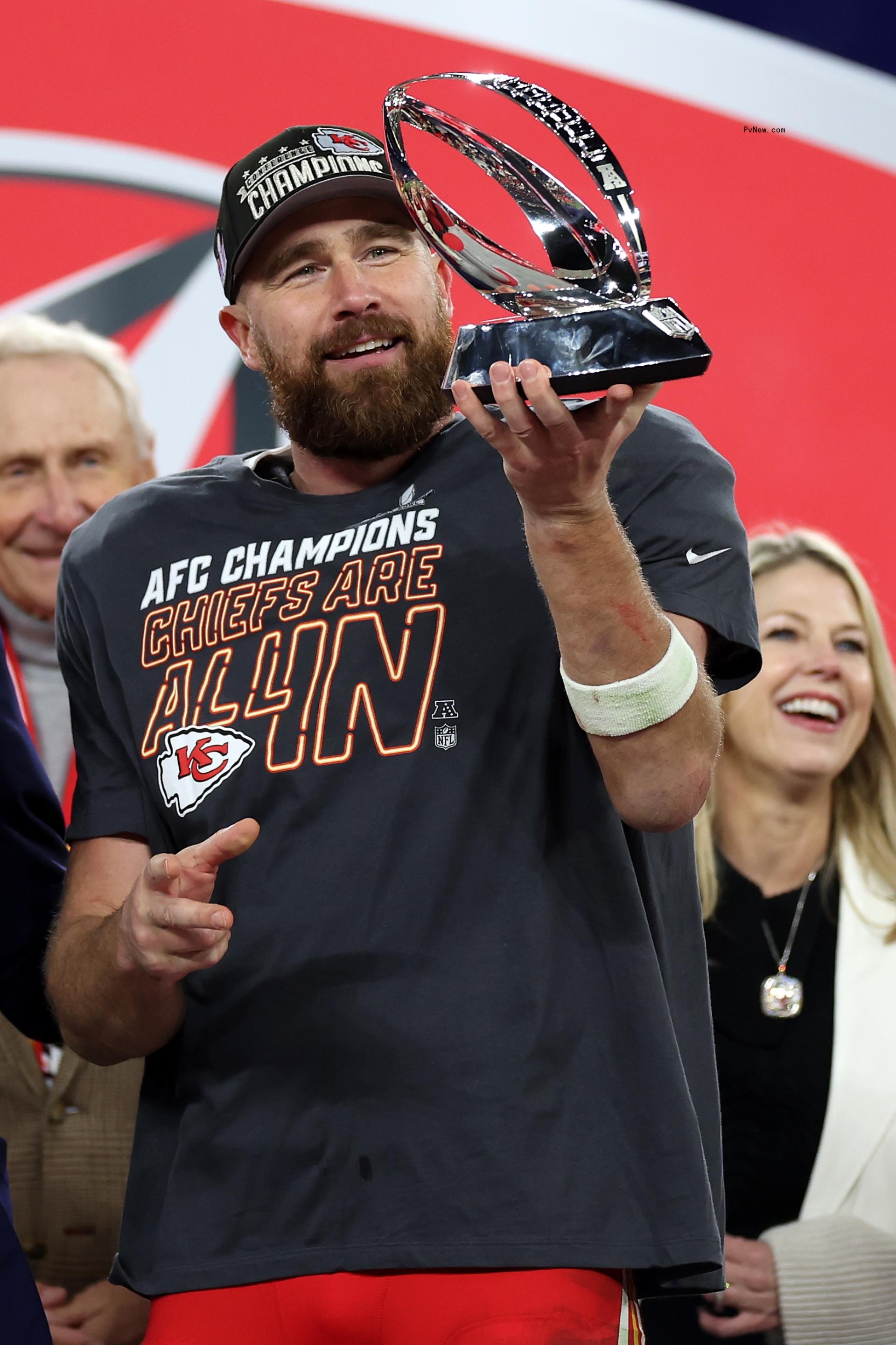 Travis Kelce holding a champio<i></i>nship trophy.