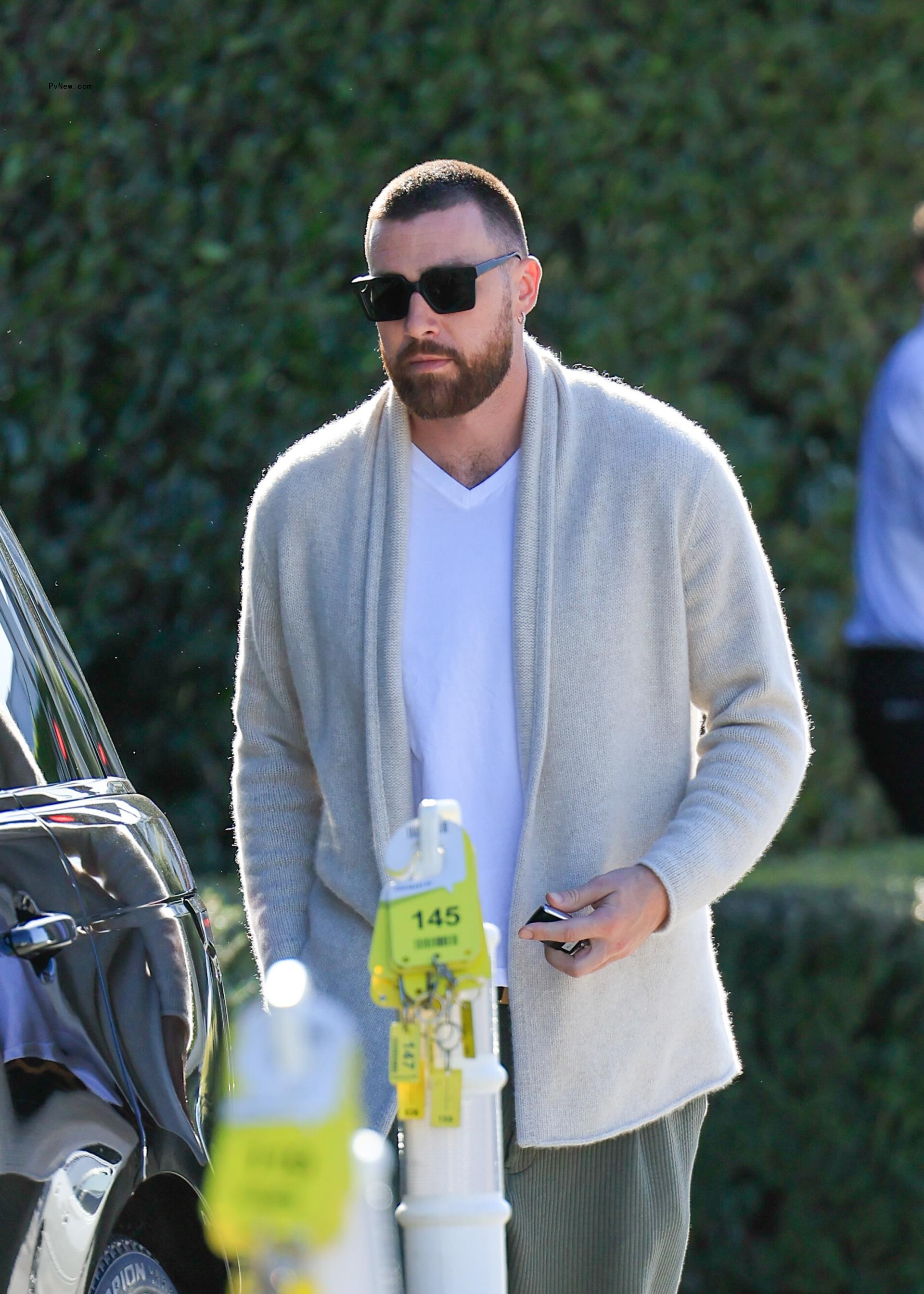 Travis Kelce wearing. a gray cardigan.