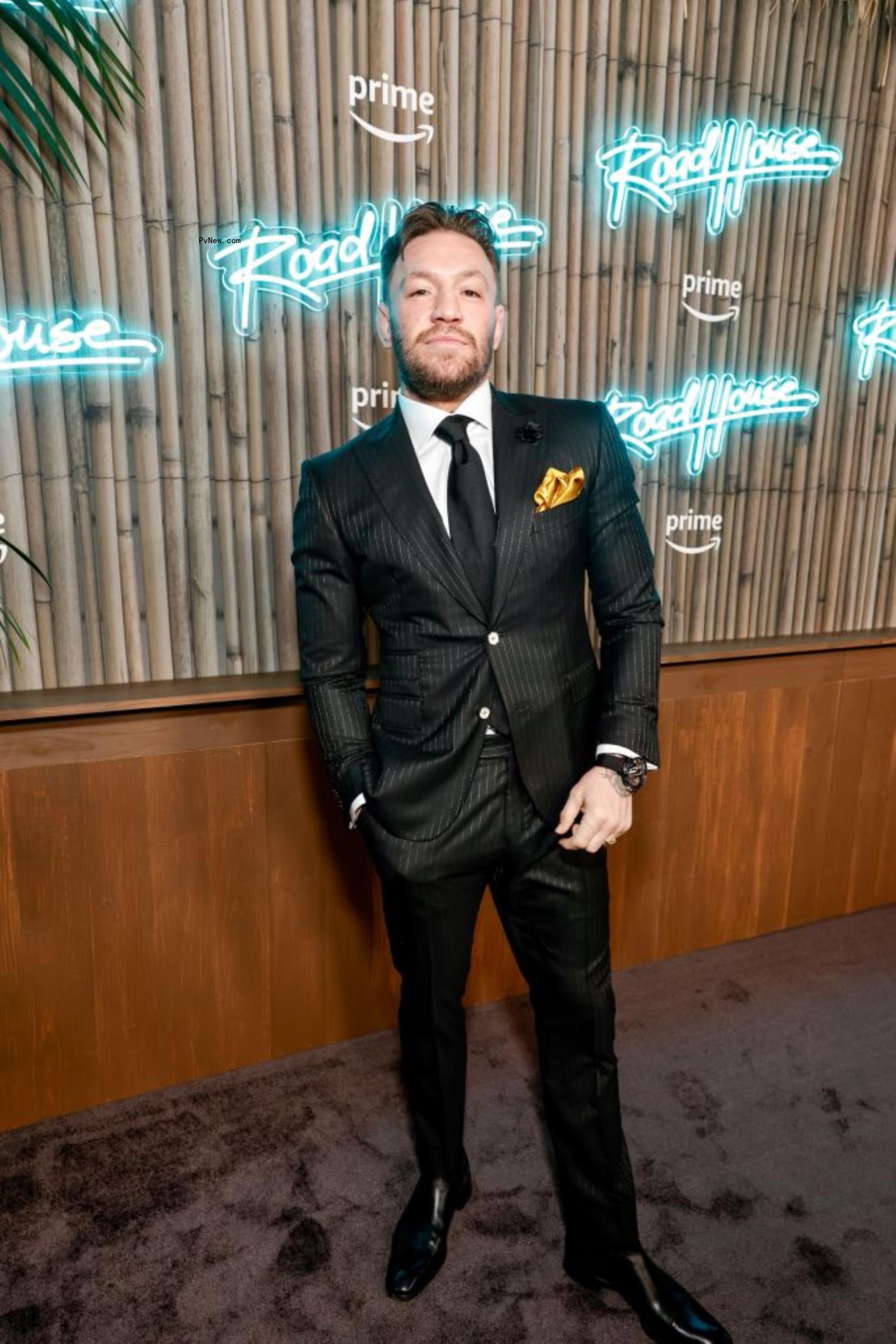 Co<i></i>nor McGregor posing in black suit.