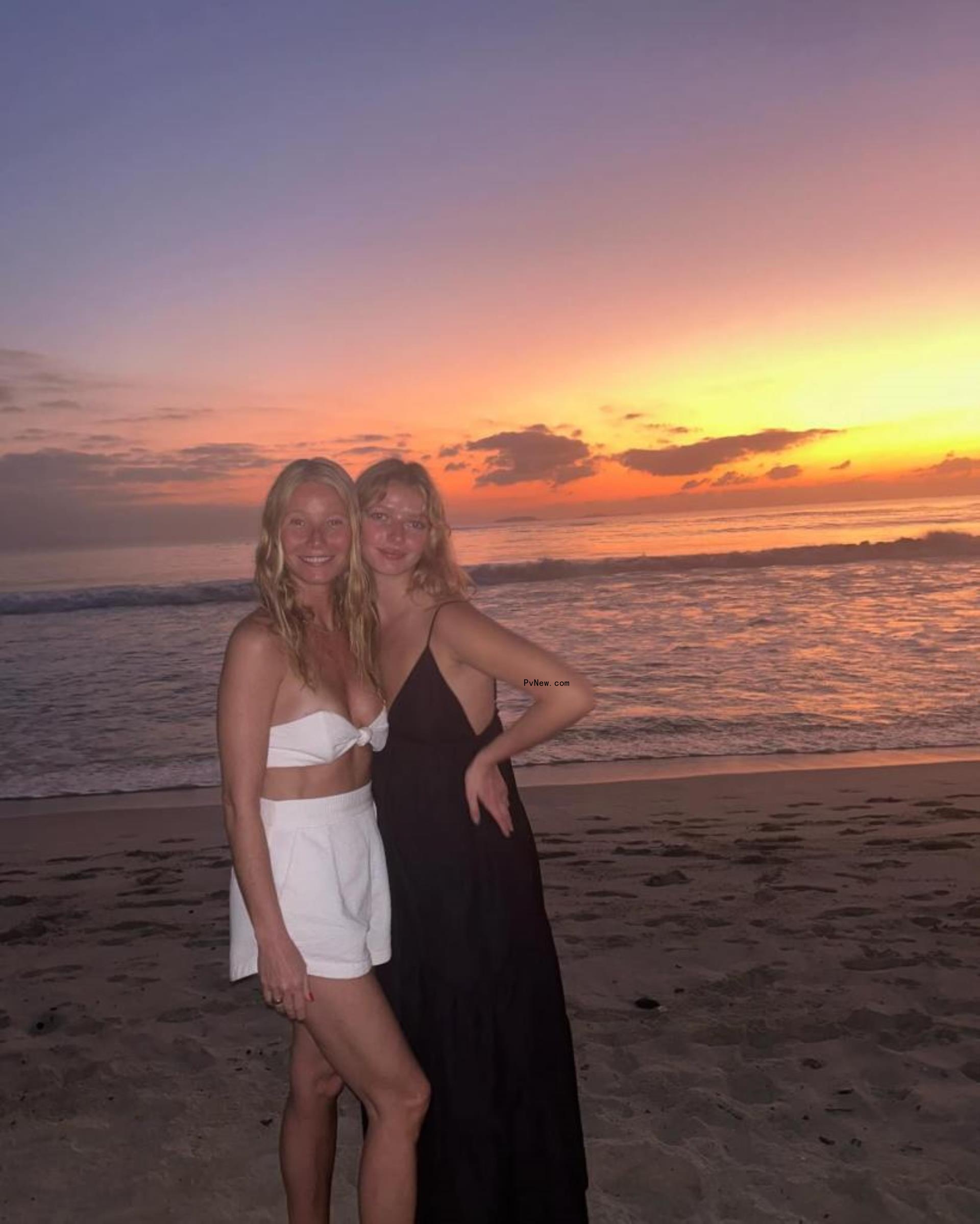 Gwyneth Paltrow and daughter Apple smiling on a beach at sunset