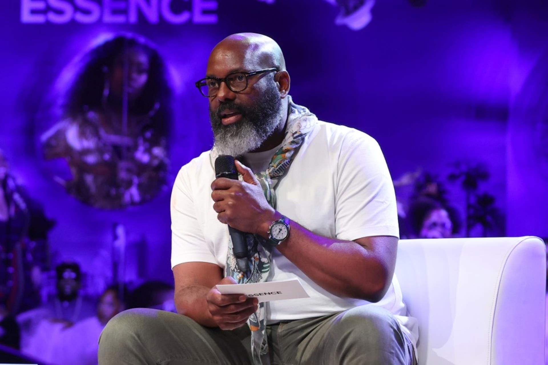 Richelieu Dennis speaking on stage with mic.