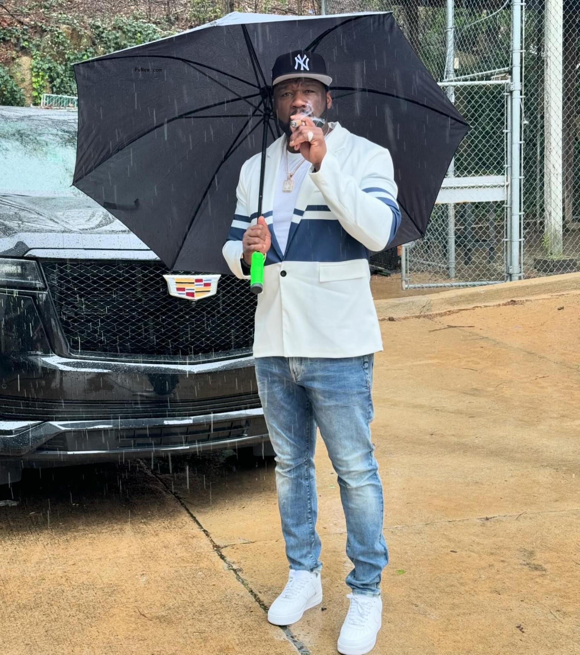 50 cent smoking a cigar under an umbrella