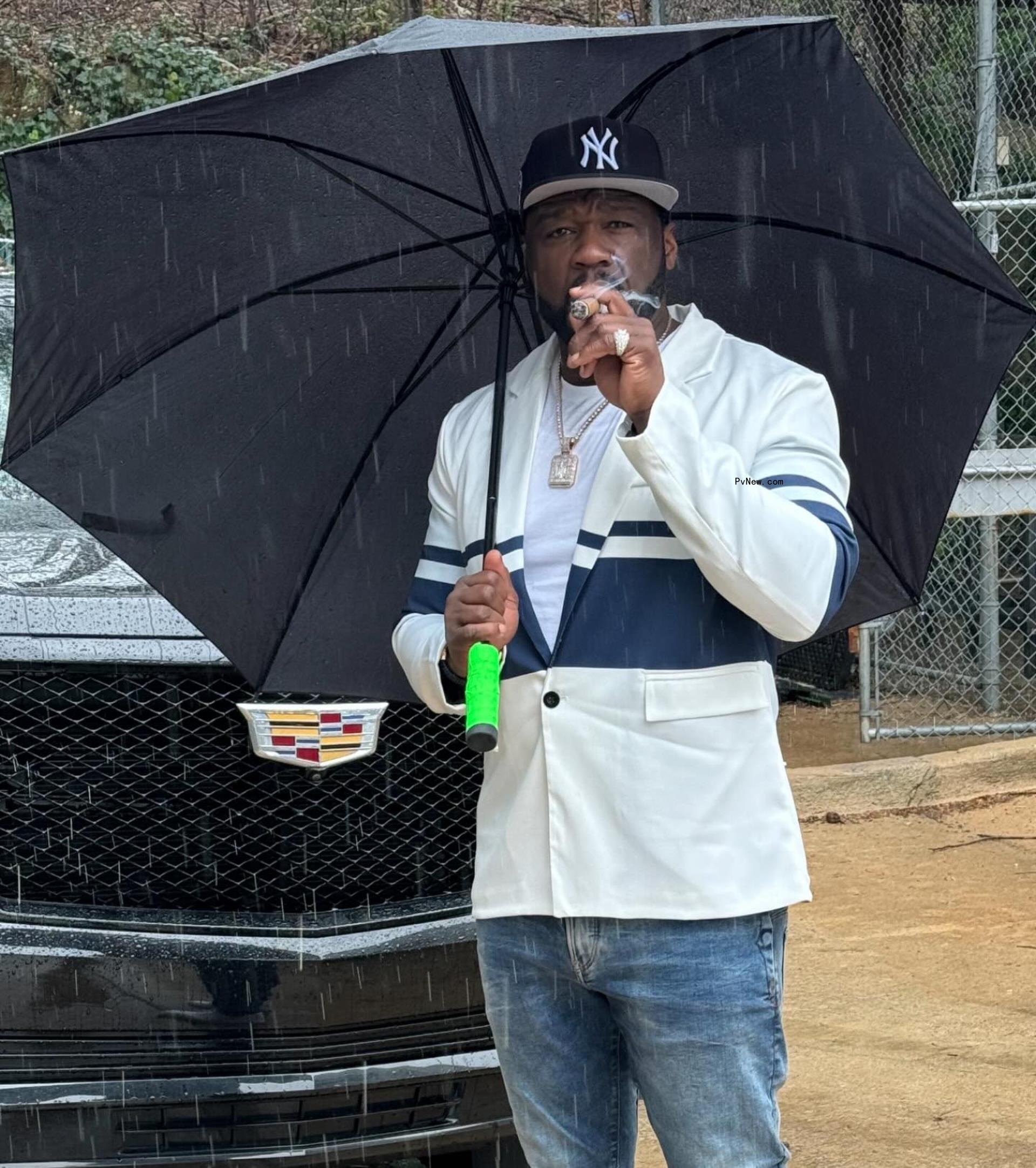50 cent smoking a cigar under an umbrella