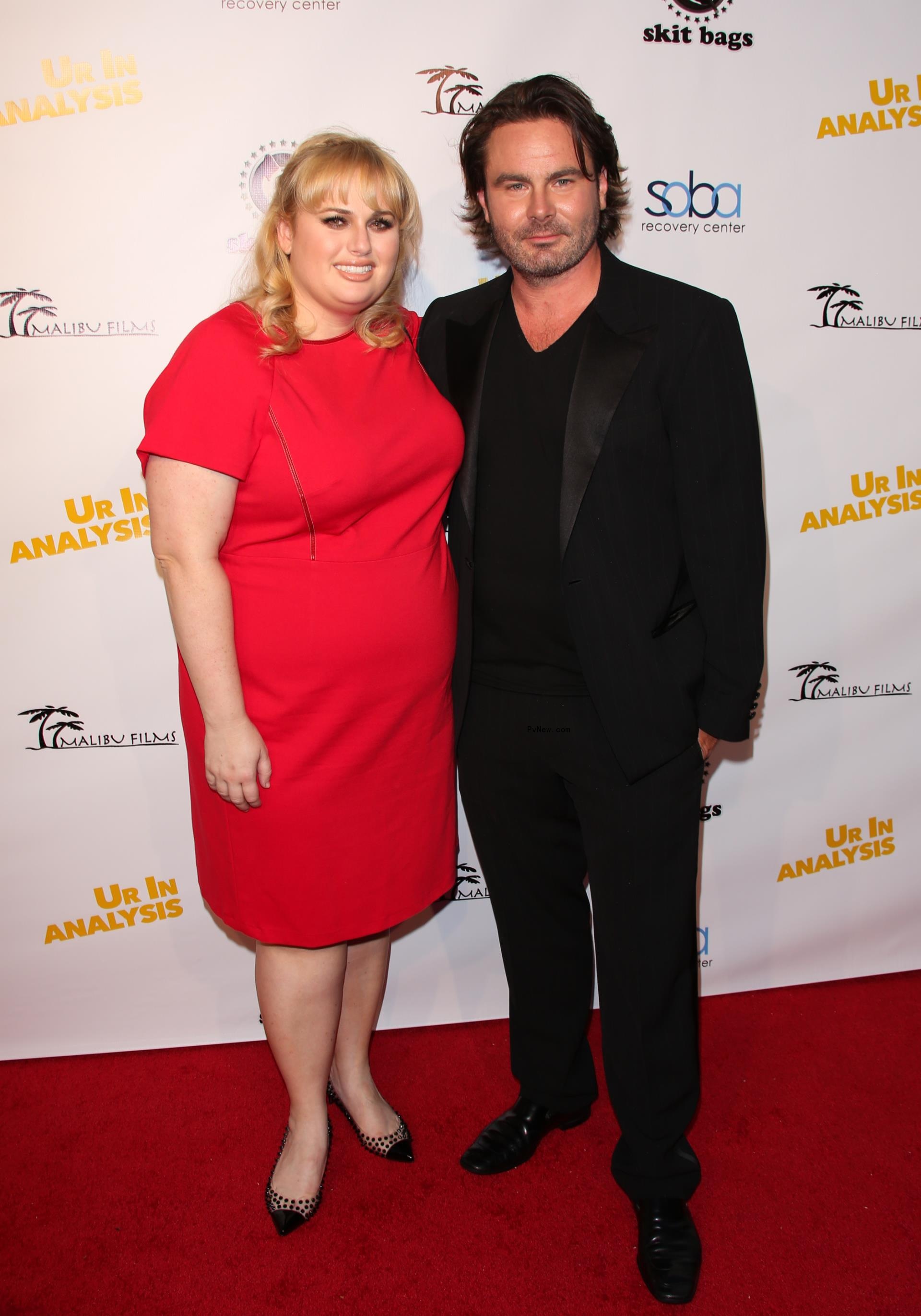 Rebel Wilson and Mickey Gooch Jr. on a red carpet.