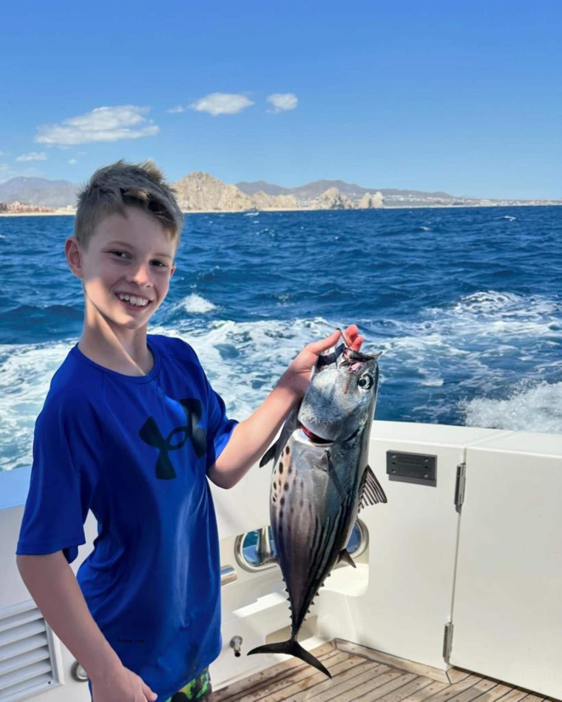 Ace holding a fish on a yacht.