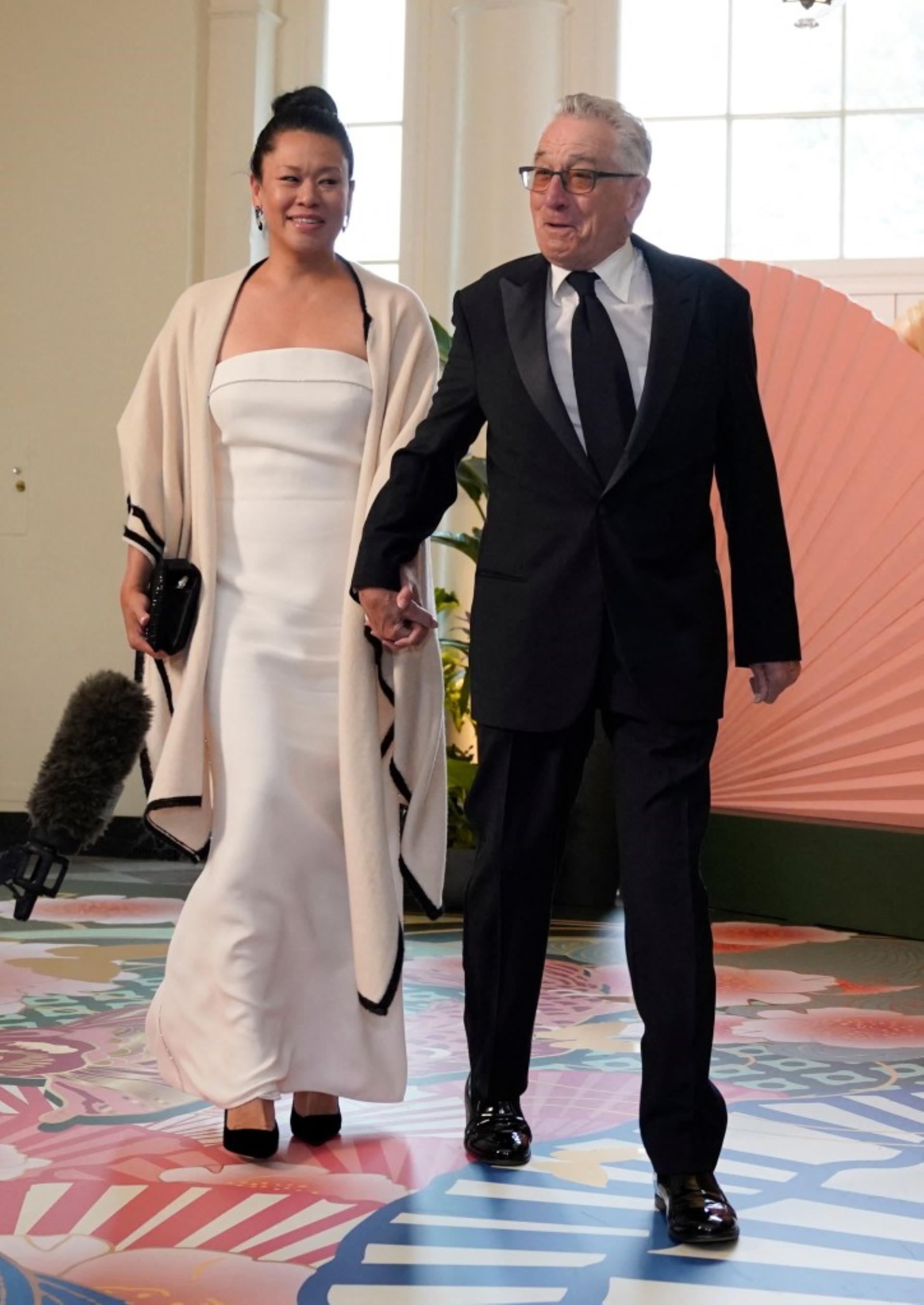 Robert De Niro  and Tiffany Chen walk while holding hands 