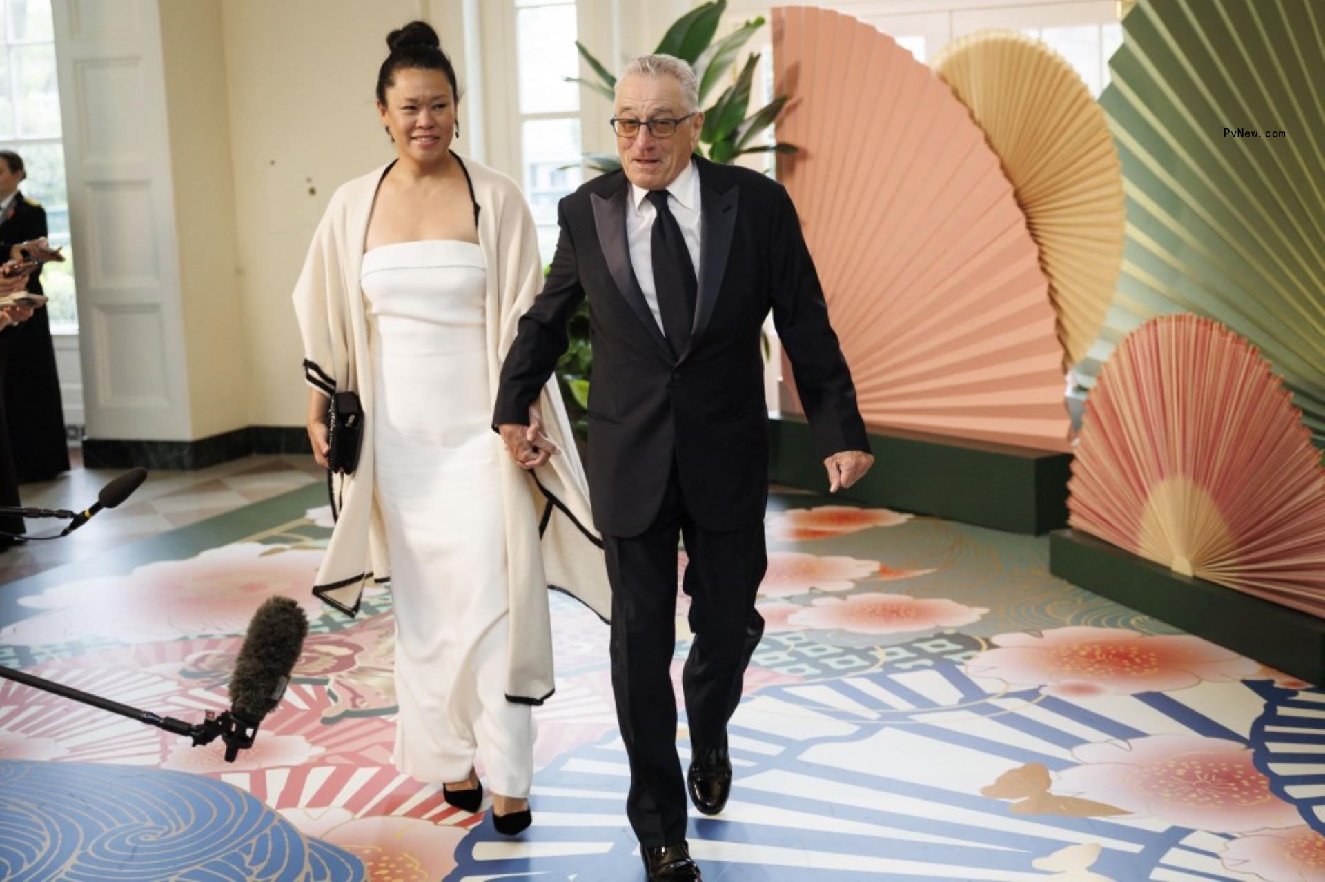 Robert De Niro  and Tiffany Chen walk while holding hands 