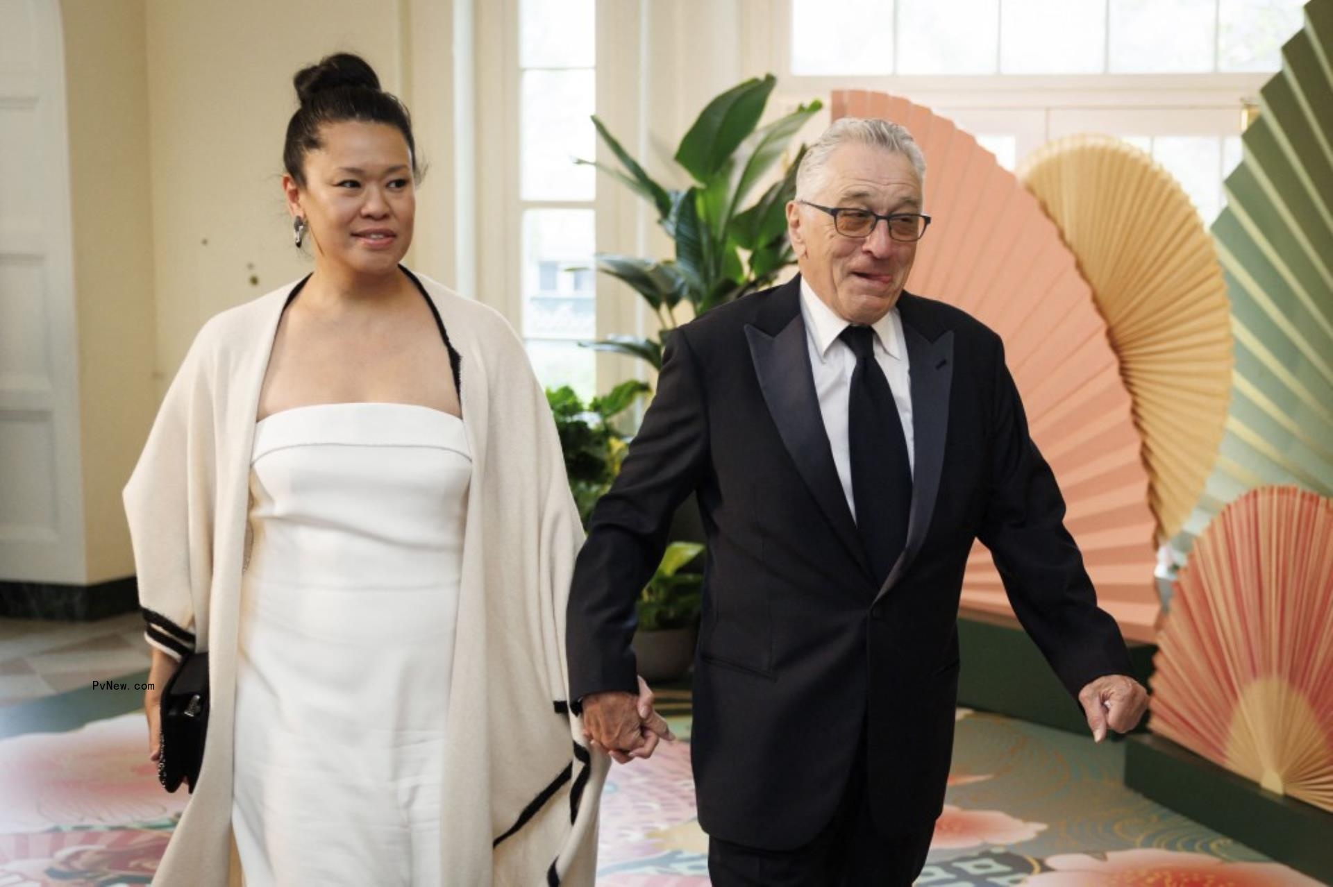 Robert De Niro  and Tiffany Chen walk while holding hands 