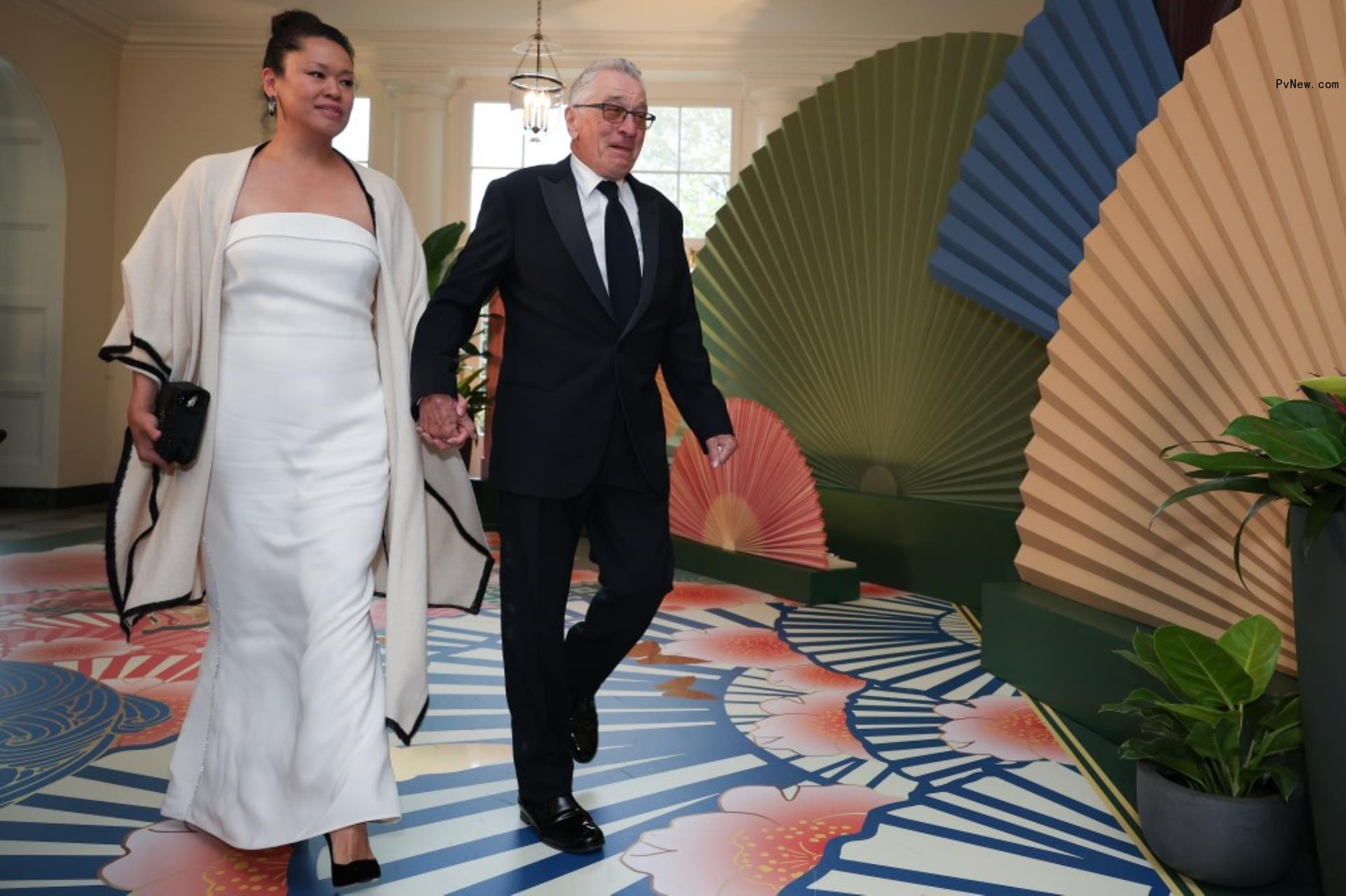 Robert De Niro  and Tiffany Chen walk while holding hands 
