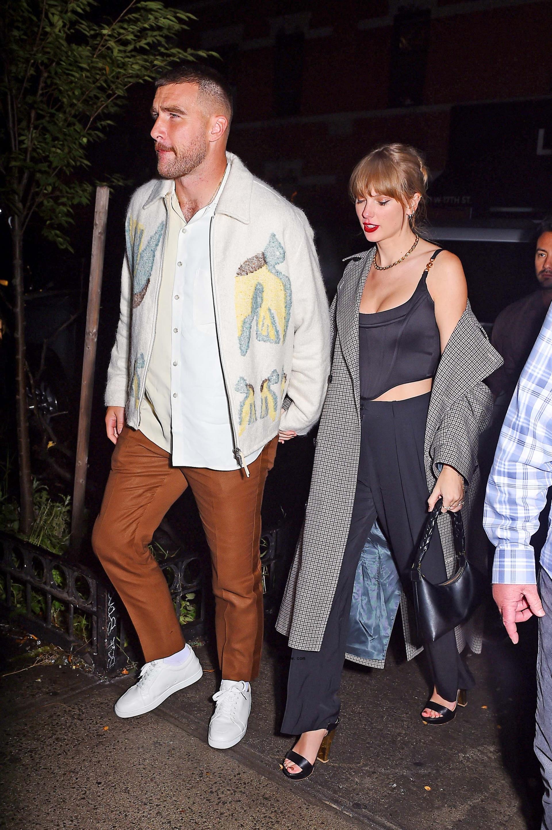 Taylor Swift and Travis Kelce holding hands.