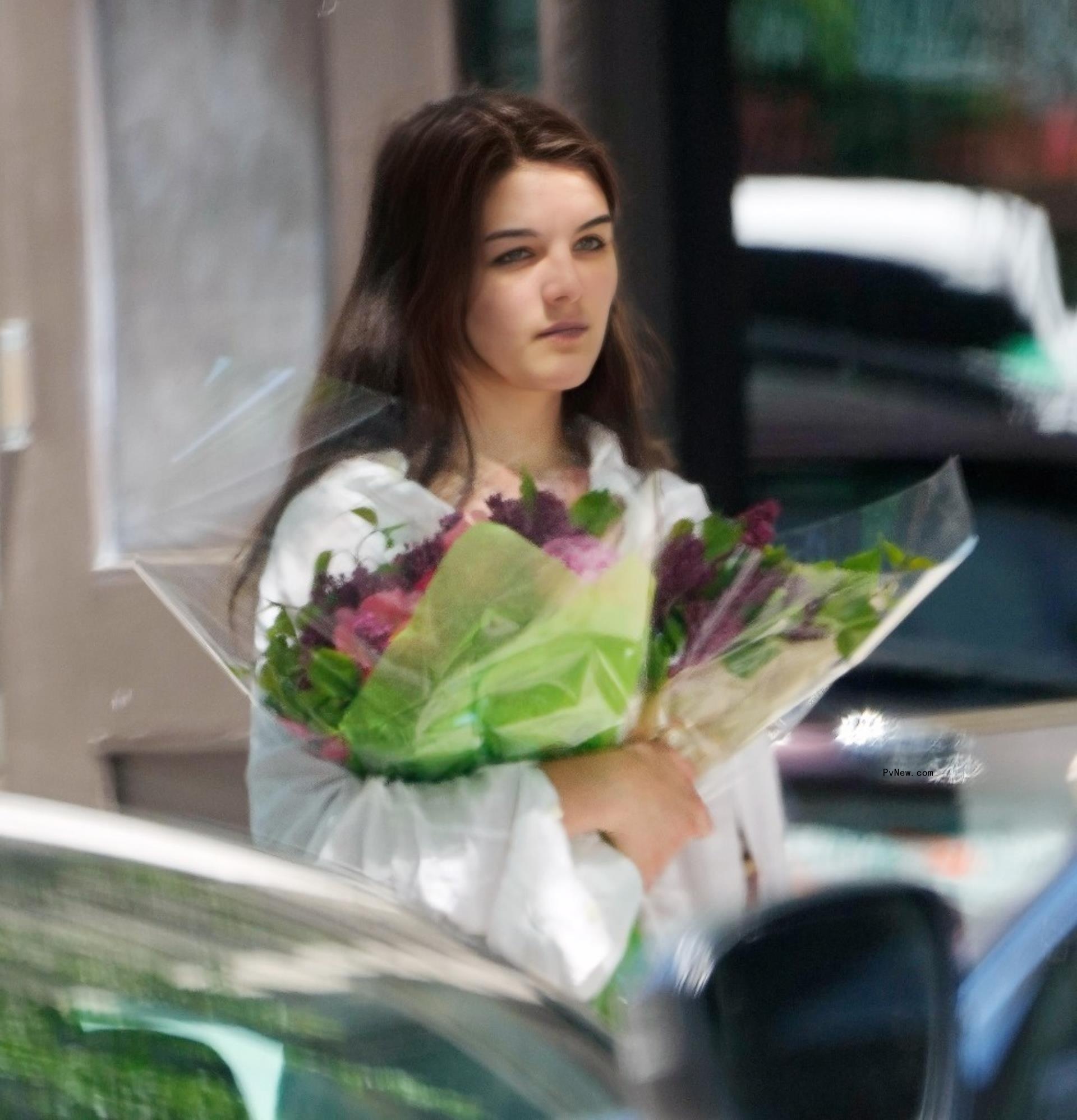 Suri Cruise holds bouquets of flowers.