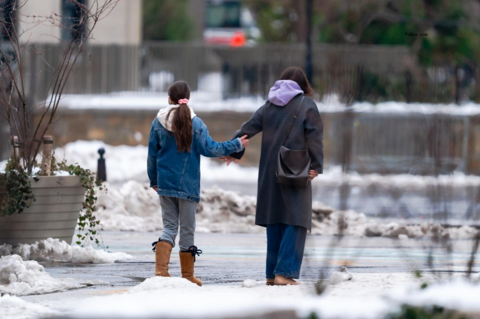 Suri Cruise smiles as she walks with her mom Katie Holmes.