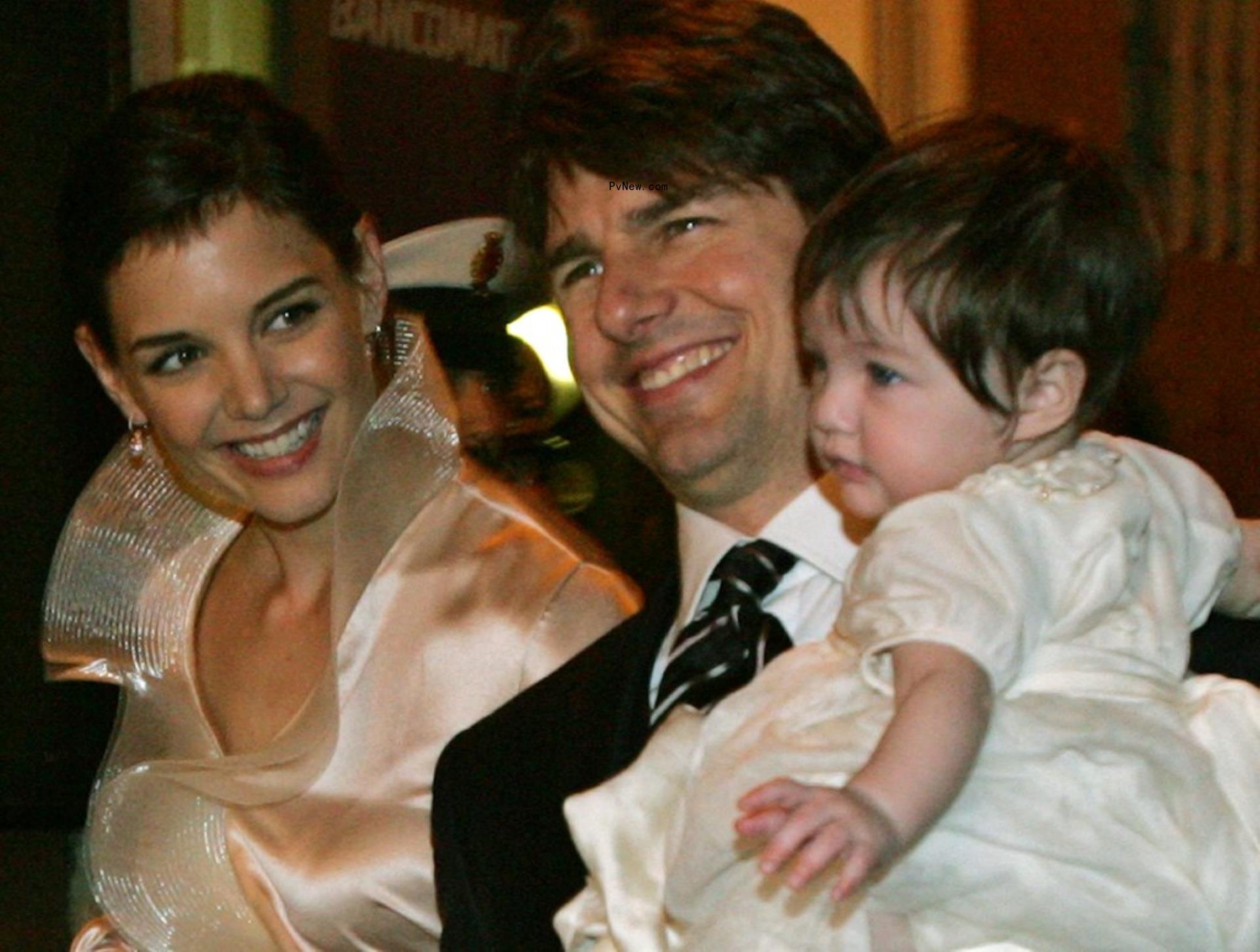 Tom Cruise smiles as he holds Suri Cruise, with Katie Holmes beside him.
