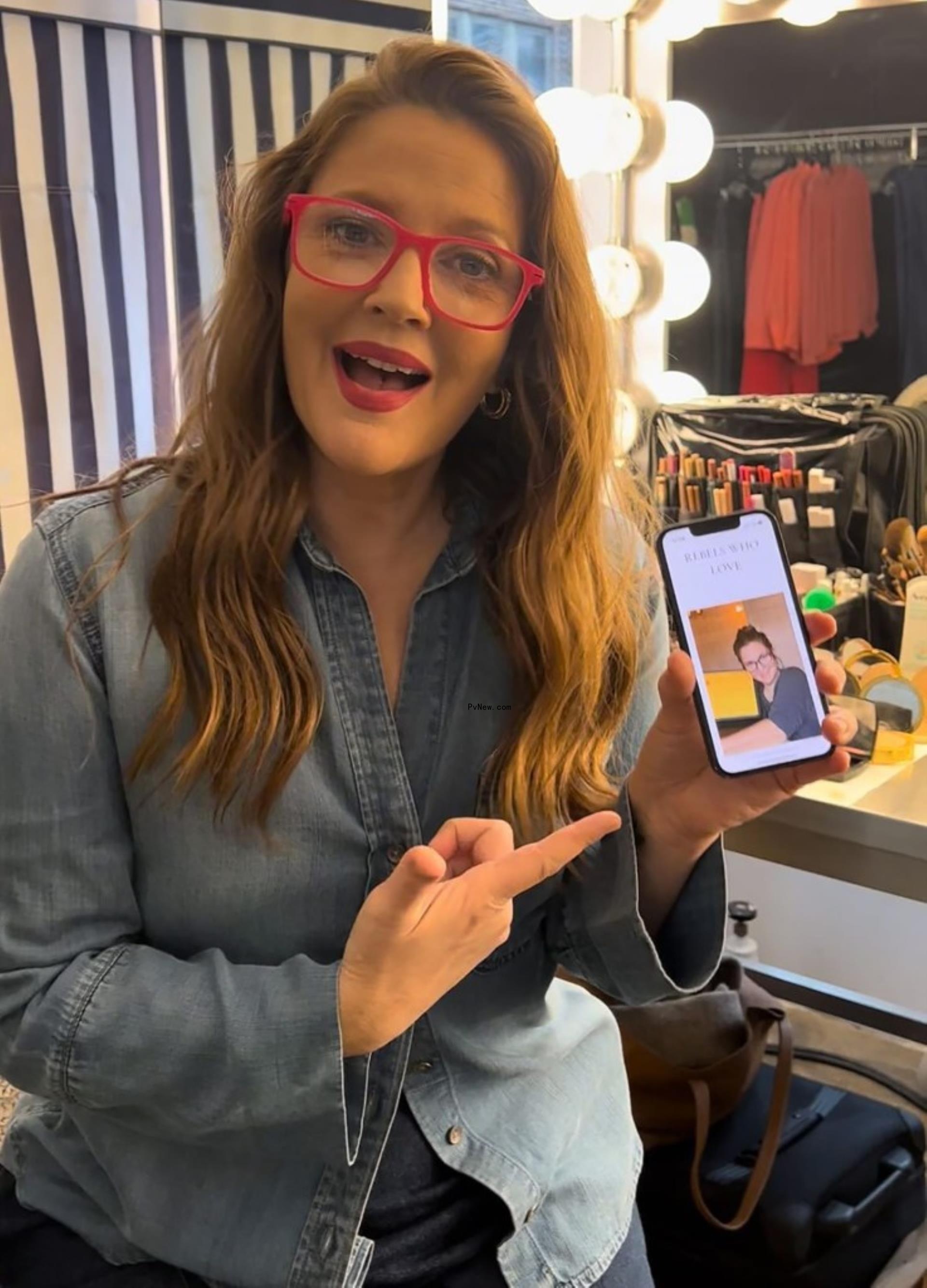 Drew Barrymore pointing to her phone.