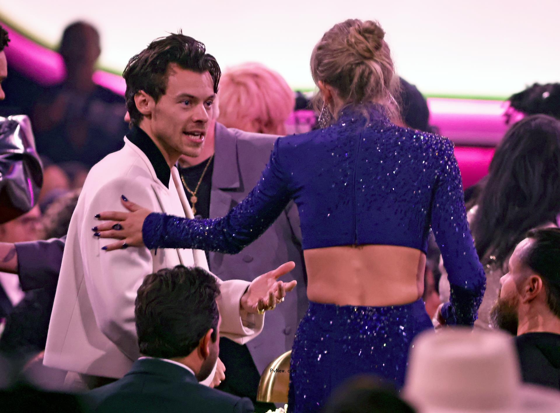 Back of Taylor Swift, with her hand on Harry Styles' shoulder
