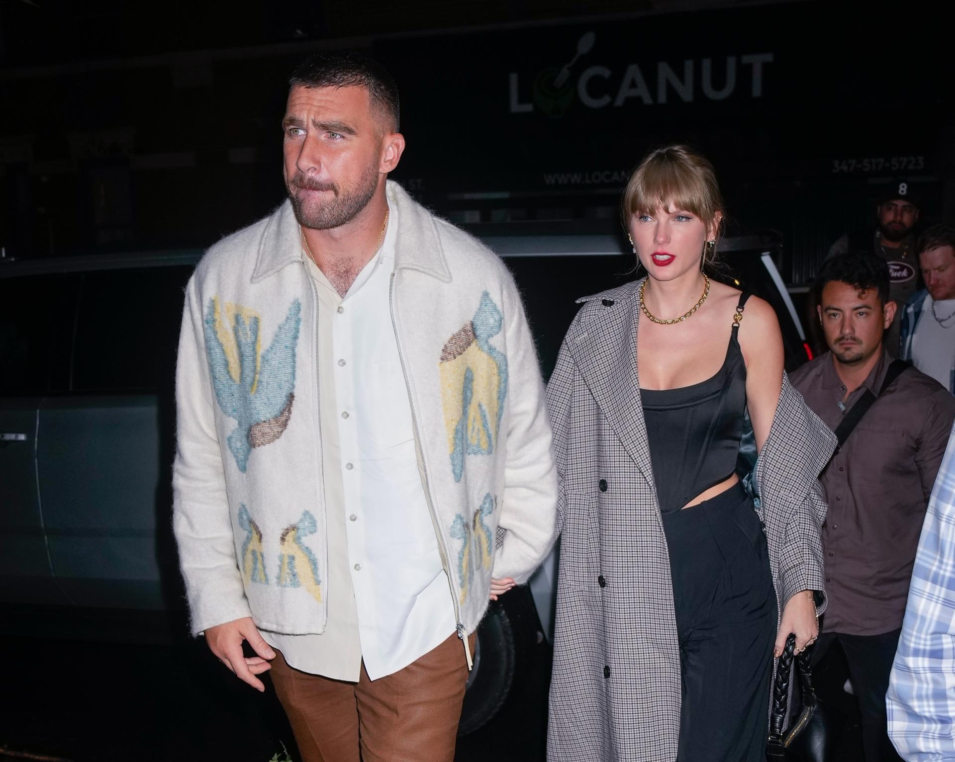 Taylor Swift kissing Travis Kelce's cheek while standing next to Chariah Gordon and Mecole Hardman.
