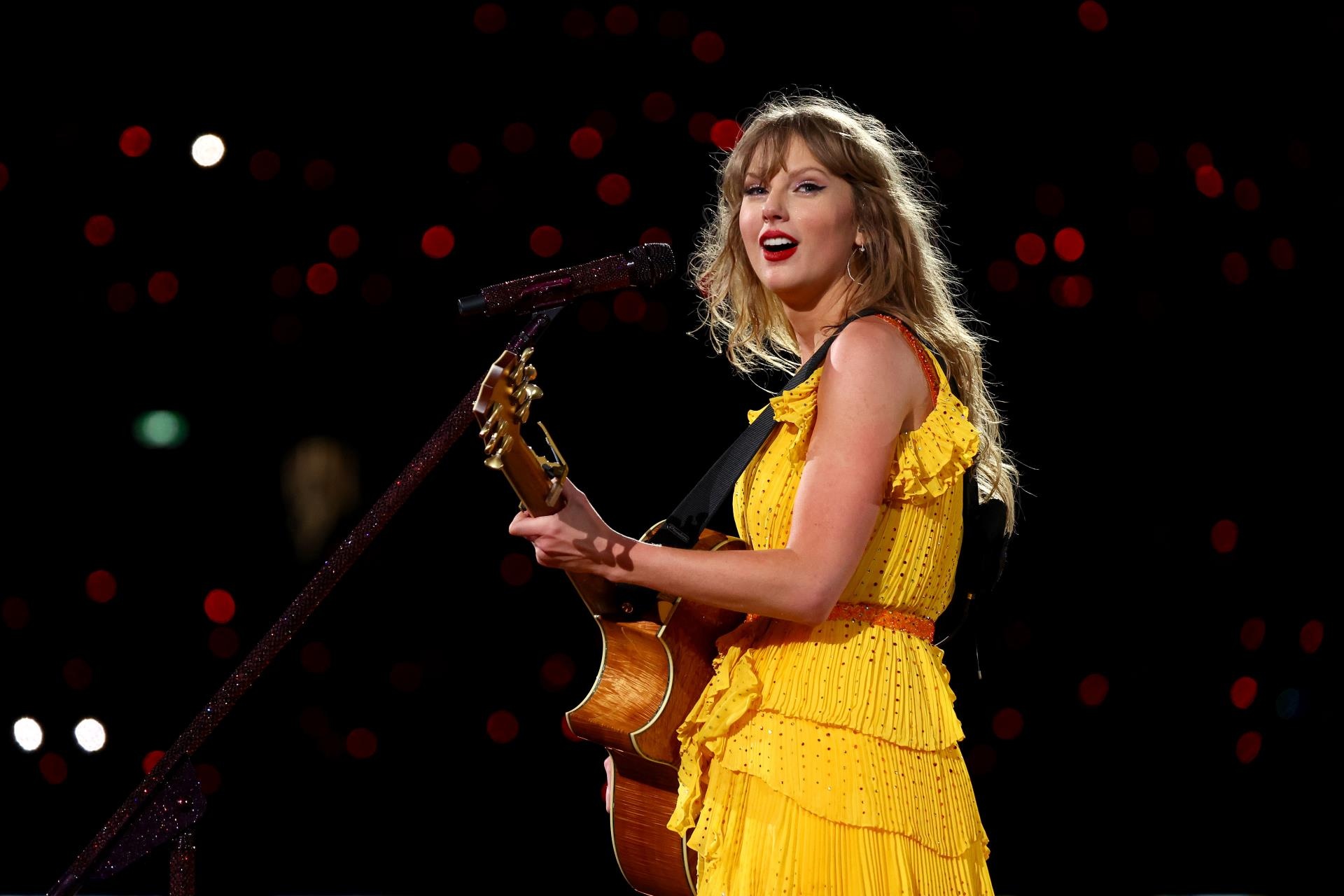 Taylor Swift performing in a yellow dress.