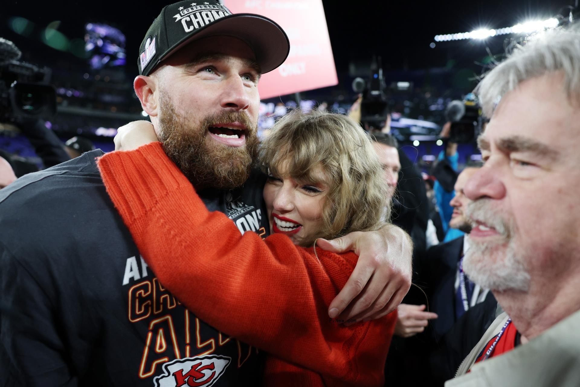 Taylor Swift hugging Travis Kelce with his dad, Ed Kelce, to the side.