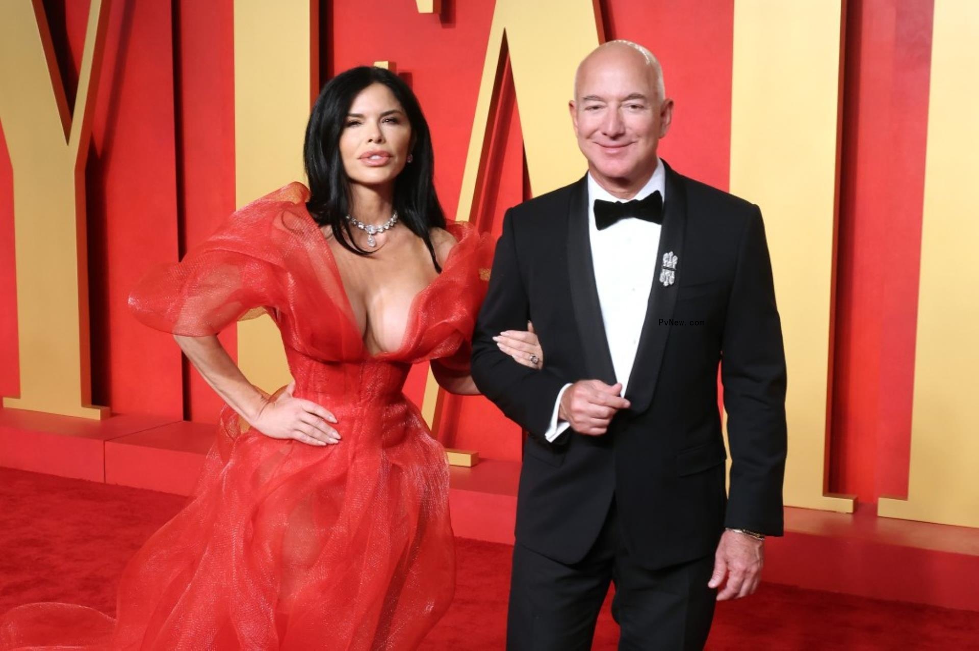 Lauren Sanchez, in red dress, l<i></i>inks arms with Jeff Bezos, in a tuxedo.
