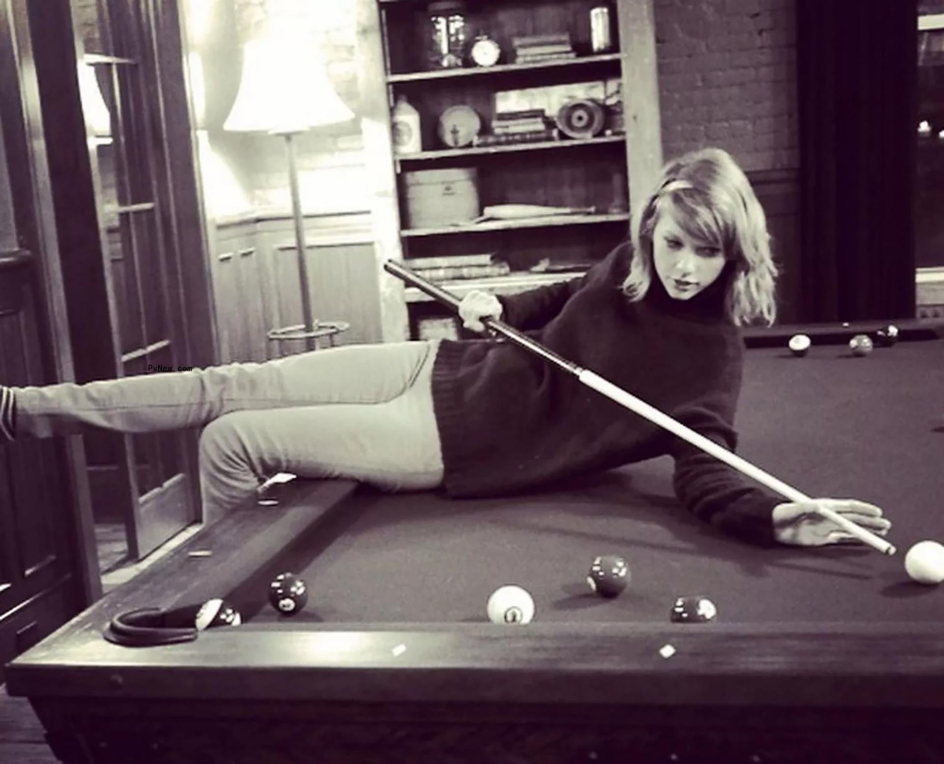 Taylor Swift sitting on a pool table