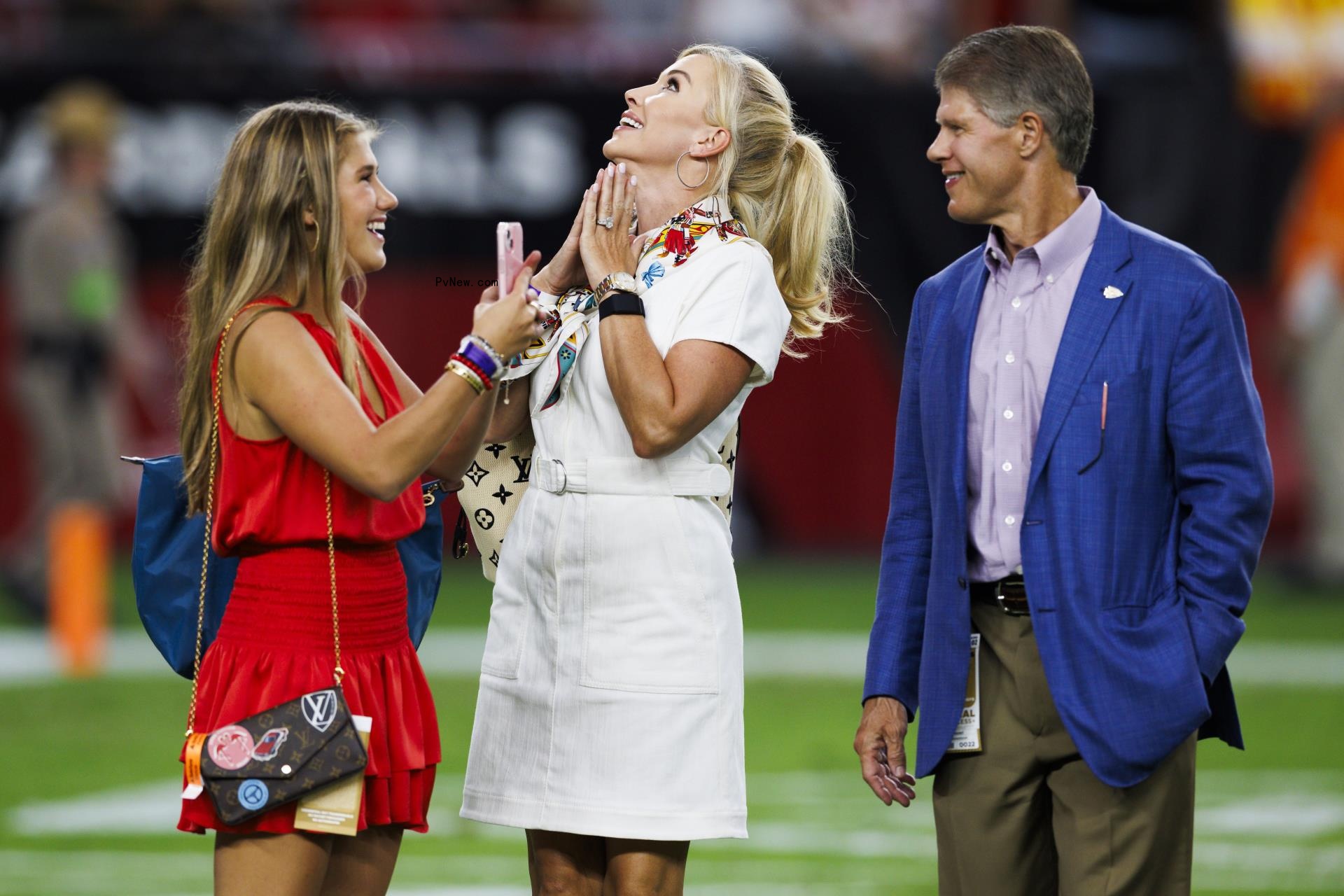 Ava Hunt and Gracie Hunt with their dad on a football field.